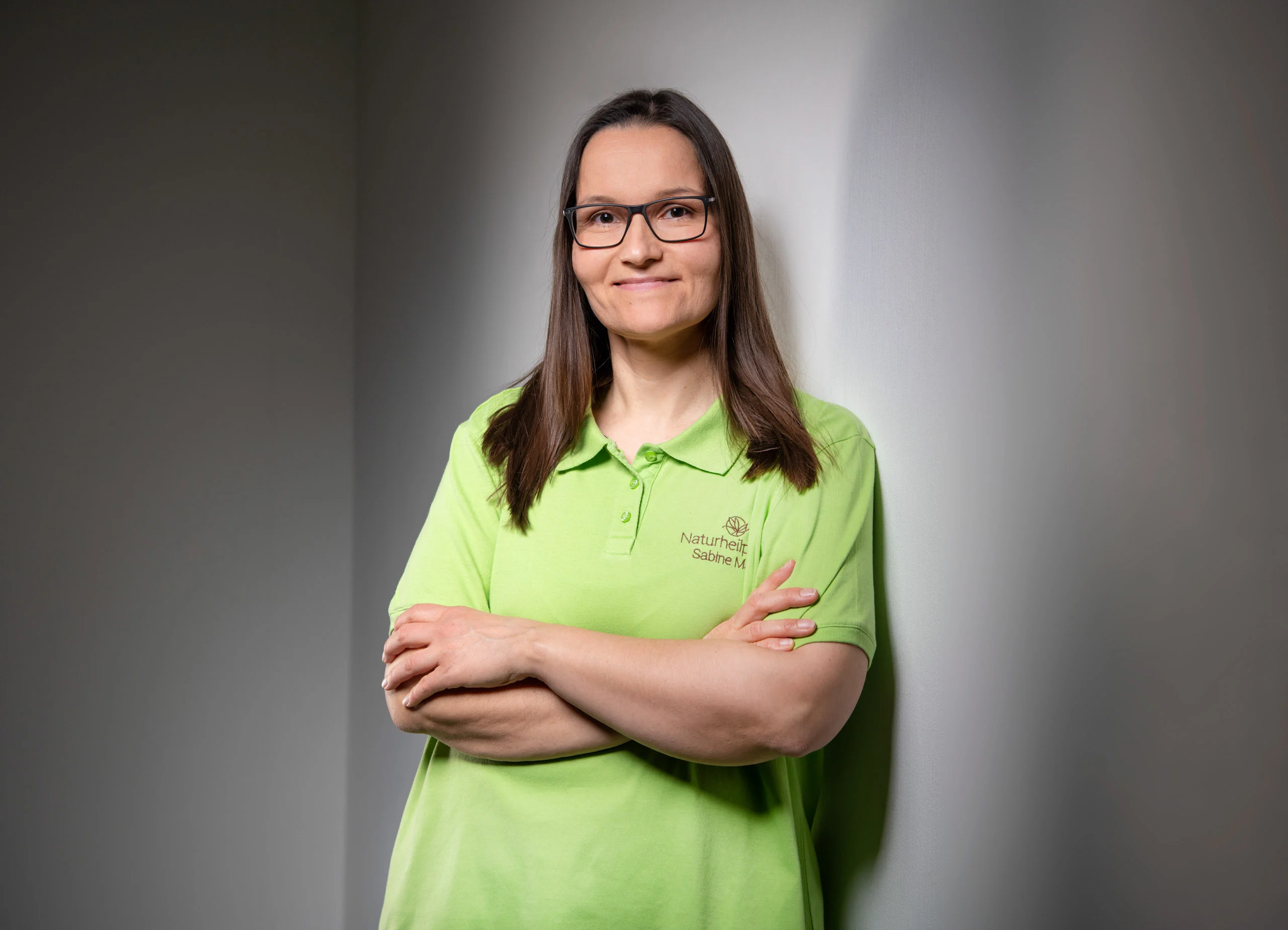 Business Portraits Fotogalerie 008 | Peter Lauritis Photography Frau mit Brille im hellgrünen Poloshirt steht mit verschränkten Armen