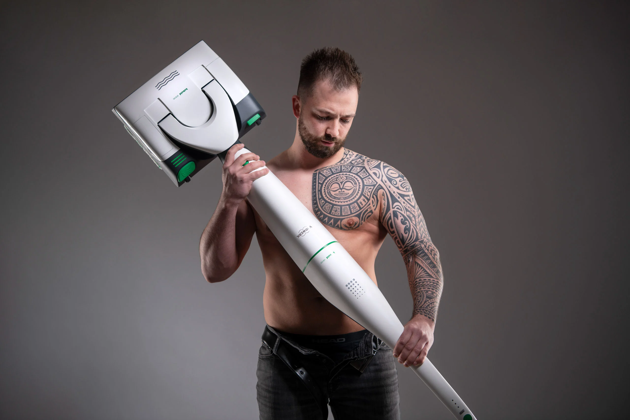 Business Portraits Fotogalerie 009 | Peter Lauritis Photography Tätowierter Mann mit nacktem Oberkörper hält einen Bodenstaubsauger wie einen Hammer