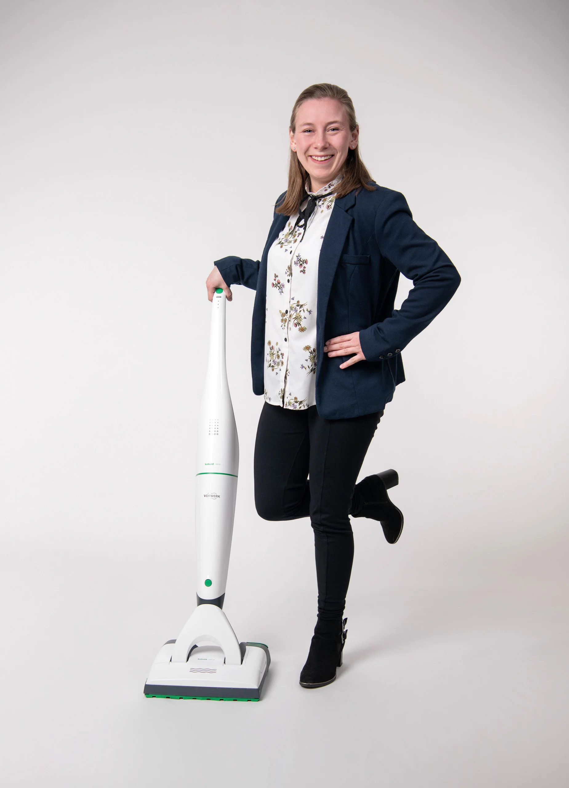 Business Portraits Fotogalerie 014 | Peter Lauritis Photography Frau im Blazer lehnt lächelnd an einem Bodenstaubsauger