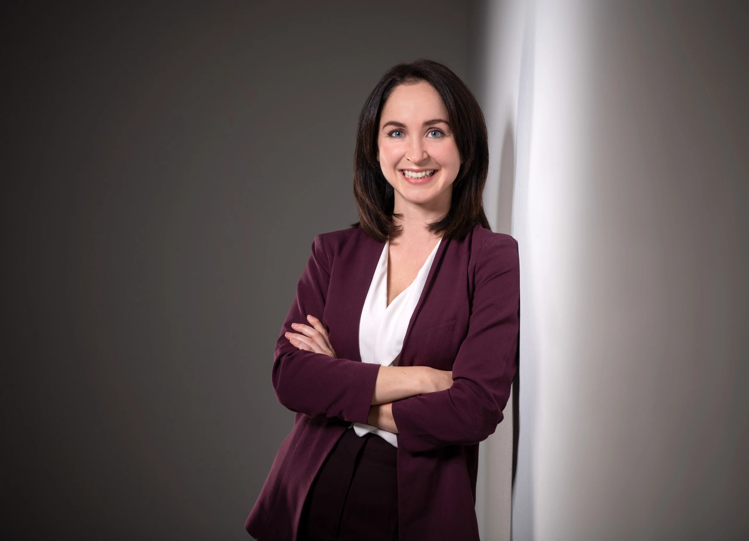 Business Portraits Fotogalerie 017 | Peter Lauritis Photography Frau im weinroten Blazer mit verschränkten Armen vor grauem Hintergrund
