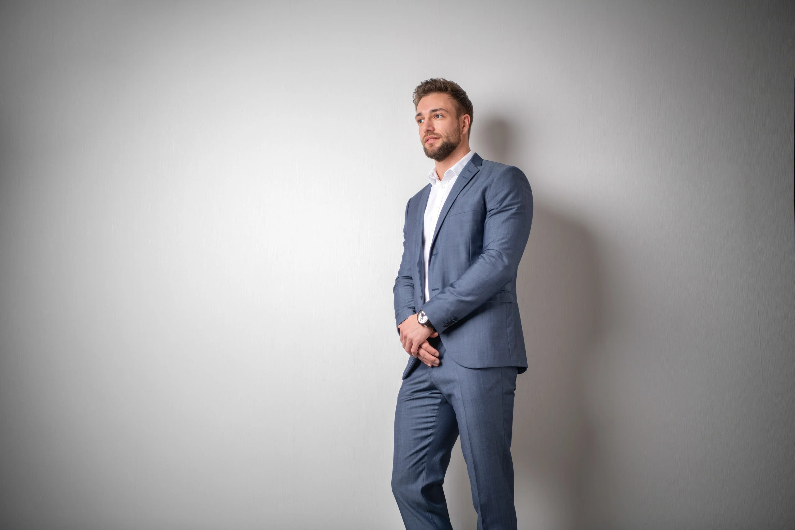 Business Portraits Fotogalerie 025 | Peter Lauritis Photography Mann im blauen Anzug steht an einer hellen Wand und blickt zur Seite
