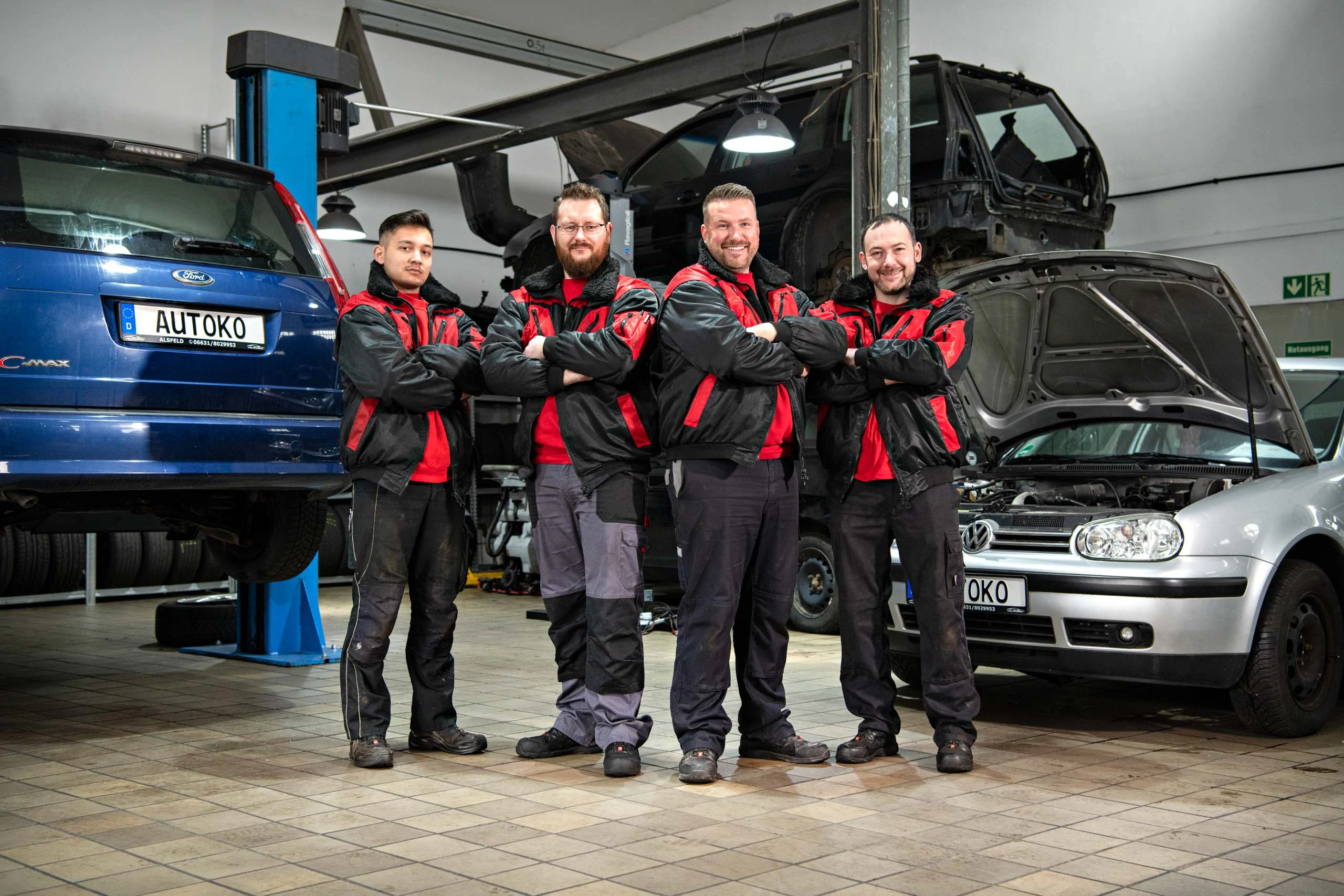 Business Portraits Fotogalerie 030 | Peter Lauritis Photography Vier Mechaniker mit verschränkten Armen vor Autos auf Hebebühnen
