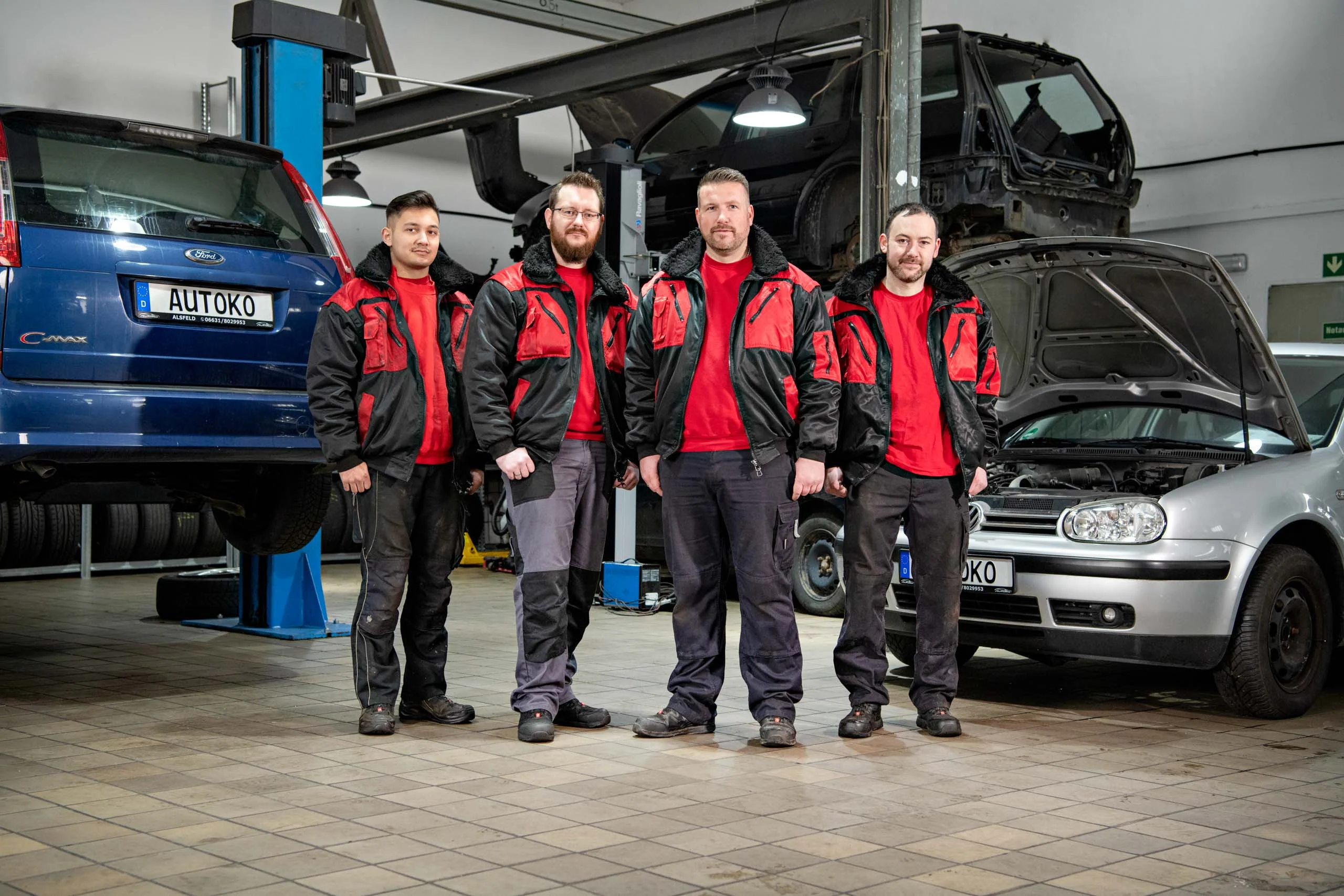 Business Portraits Fotogalerie 031 | Peter Lauritis Photography Werkstatt-Team in roten Jacken steht vor zwei Autos