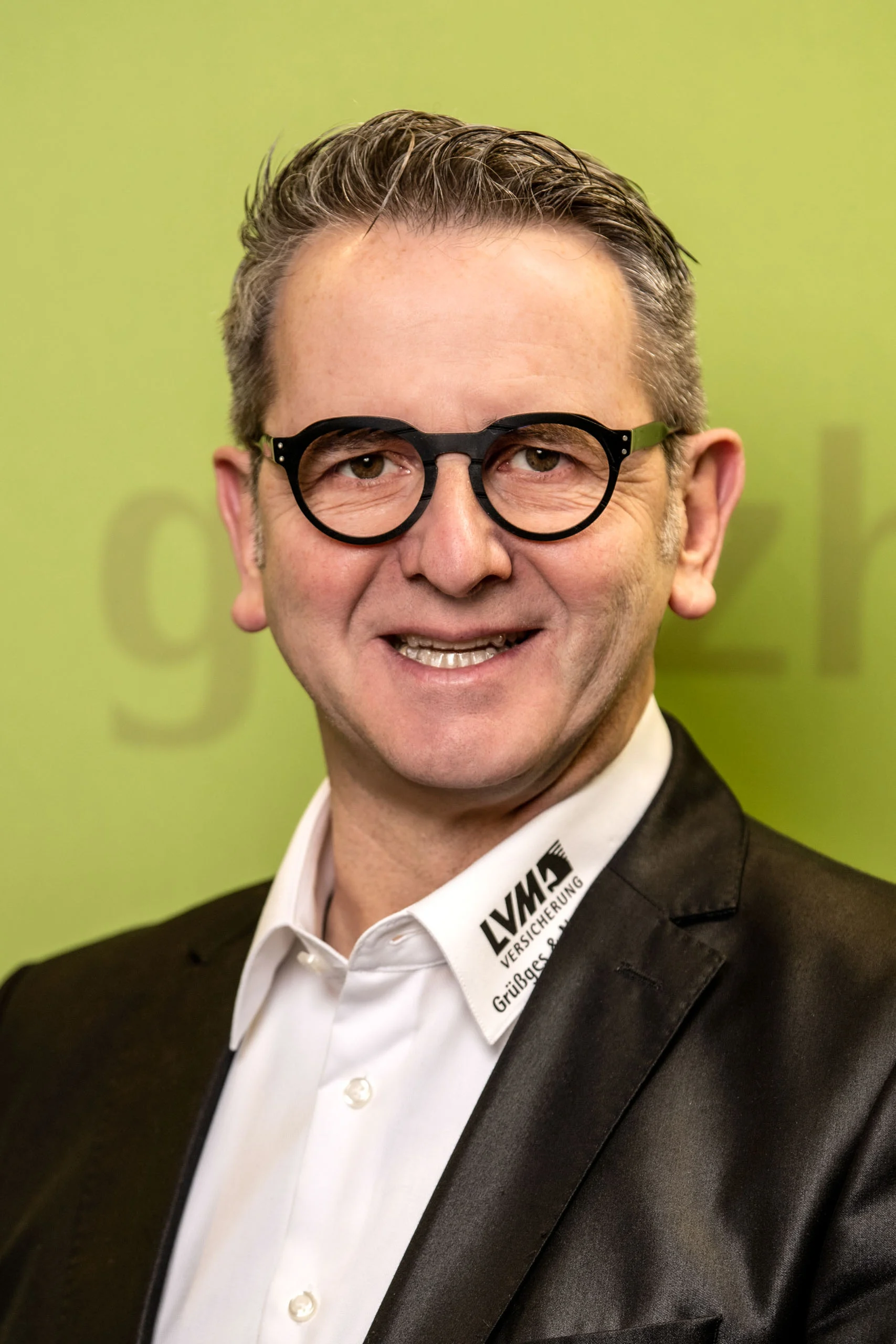 Business Portraits Fotogalerie 035 | Peter Lauritis Photography Mitarbeiterporträt: Mann mit Brille und Sakko vor grüner Wand