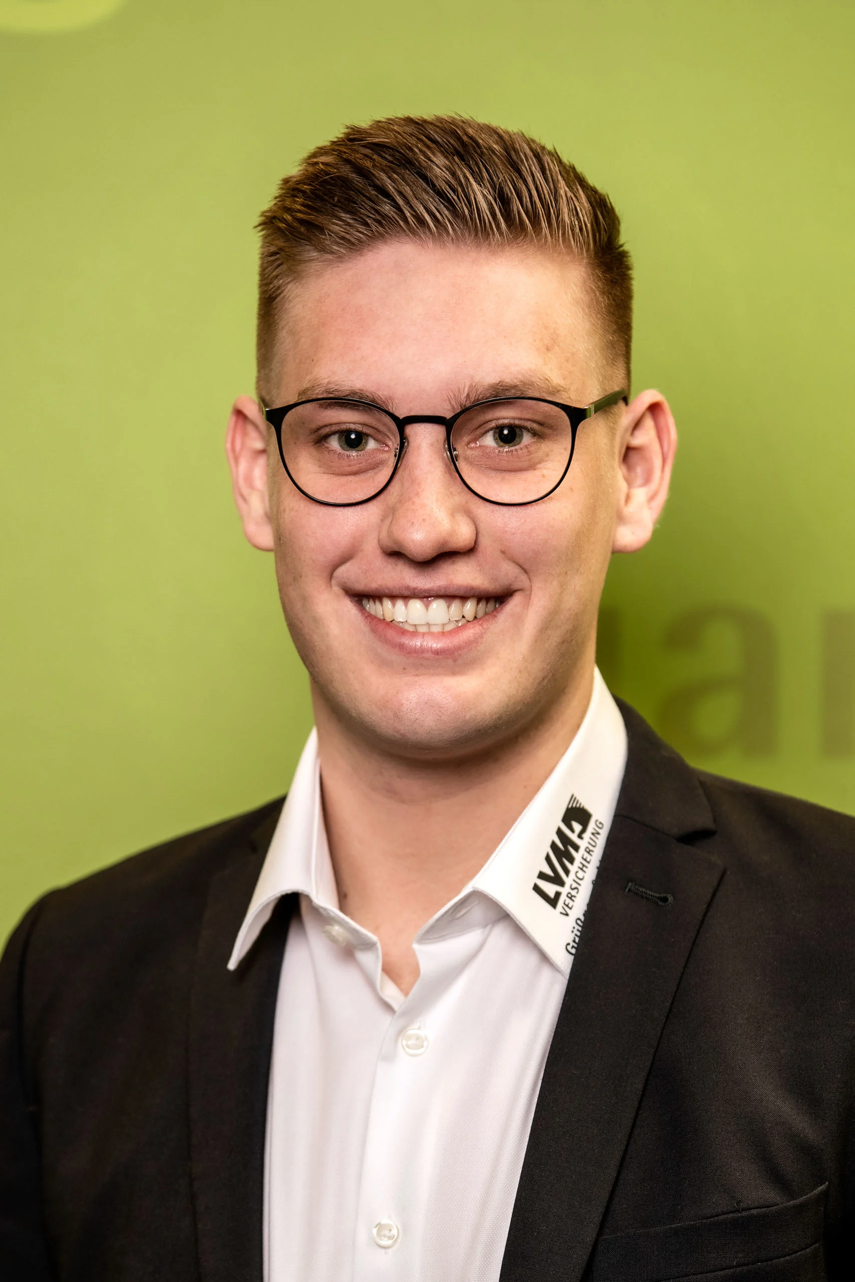 Business Portraits Fotogalerie 037 | Peter Lauritis Photography Mitarbeiterporträt: junger Mann mit Brille vor grüner Wand