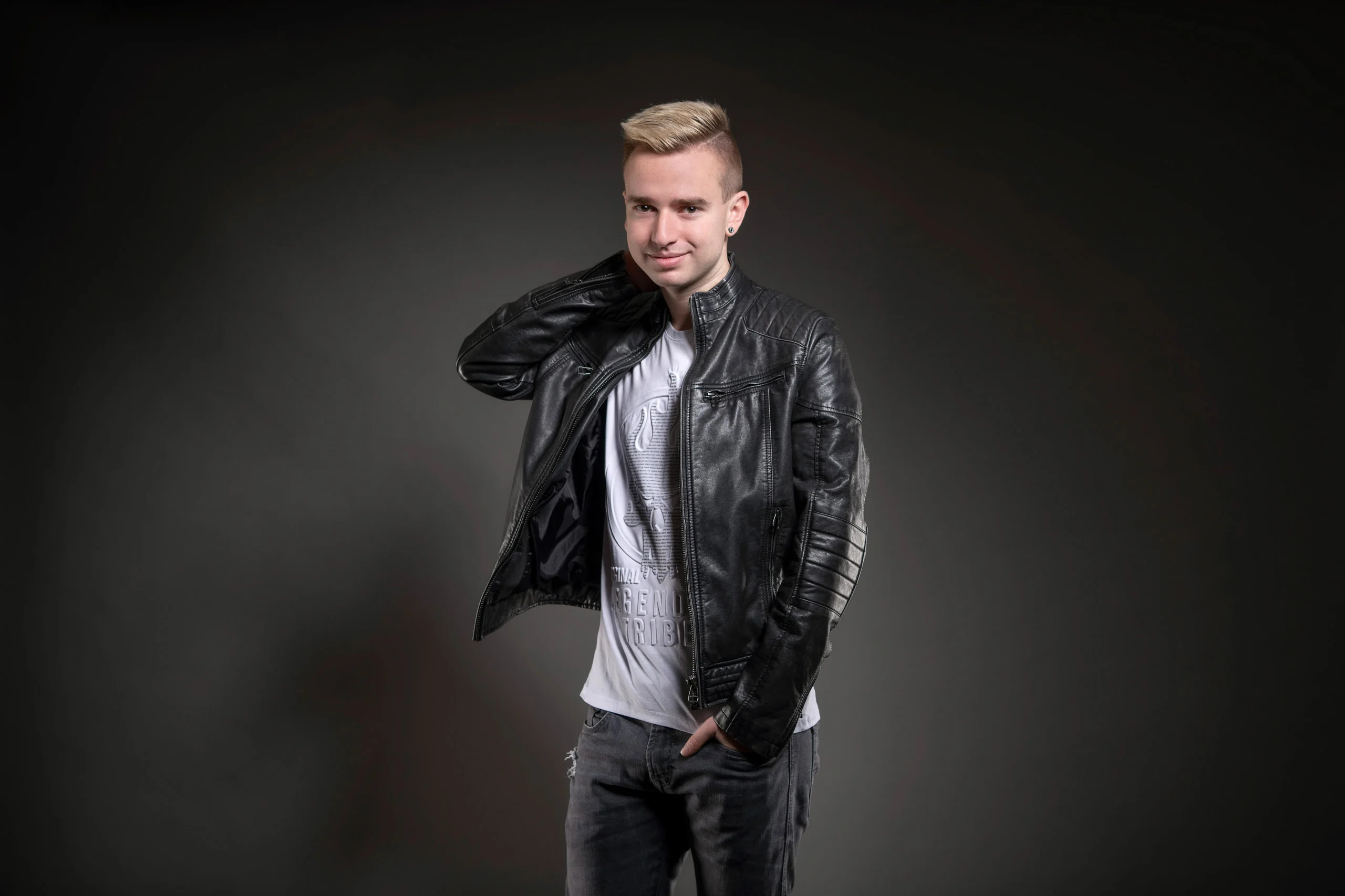 Business Portraits Fotogalerie 049 | Peter Lauritis Photography Junger Mann in Lederjacke greift sich an den Kragen, dunkler Hintergrund
