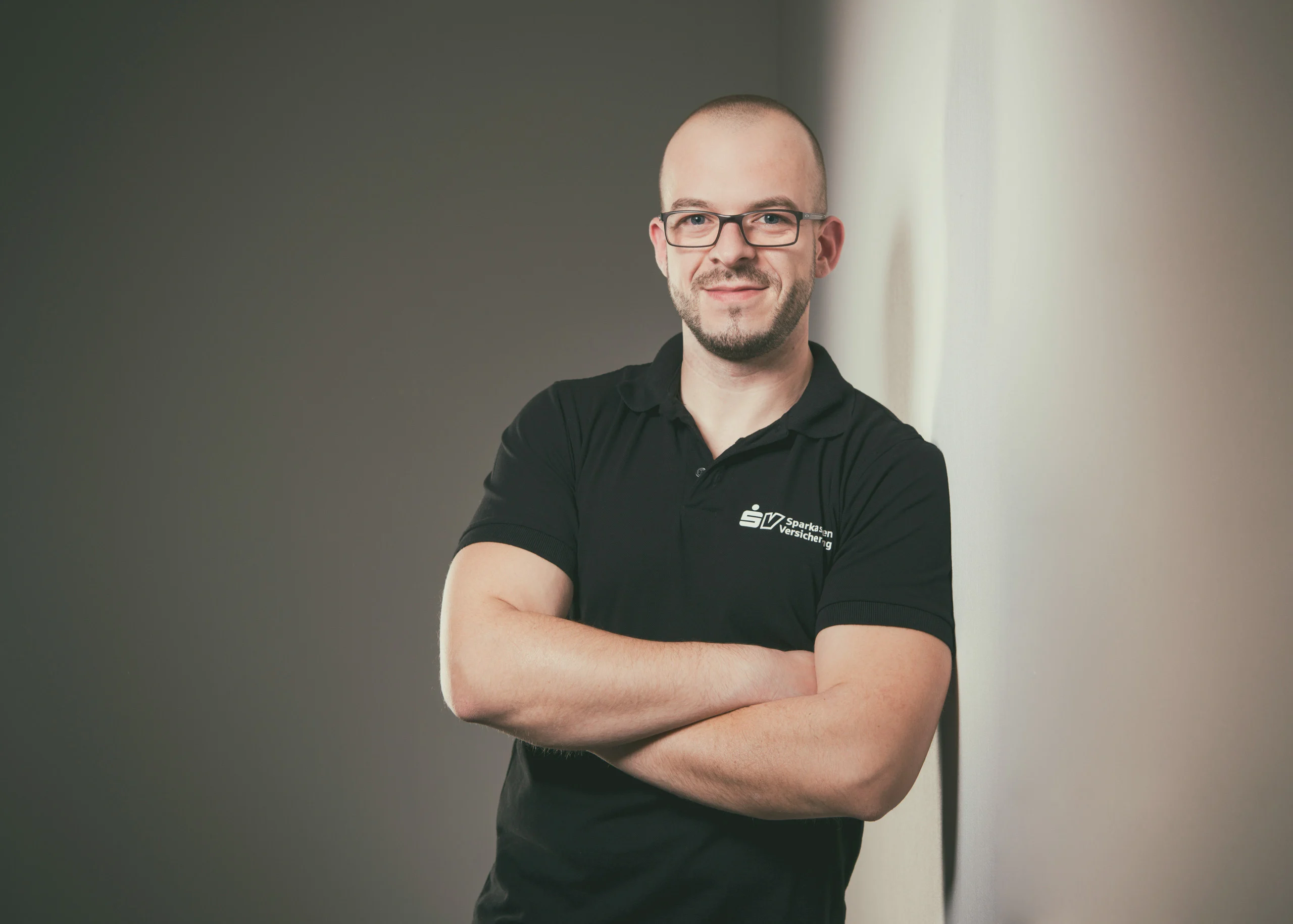 Business Portraits Fotogalerie 050 | Peter Lauritis Photography Mann mit Brille im schwarzen Poloshirt mit verschränkten Armen