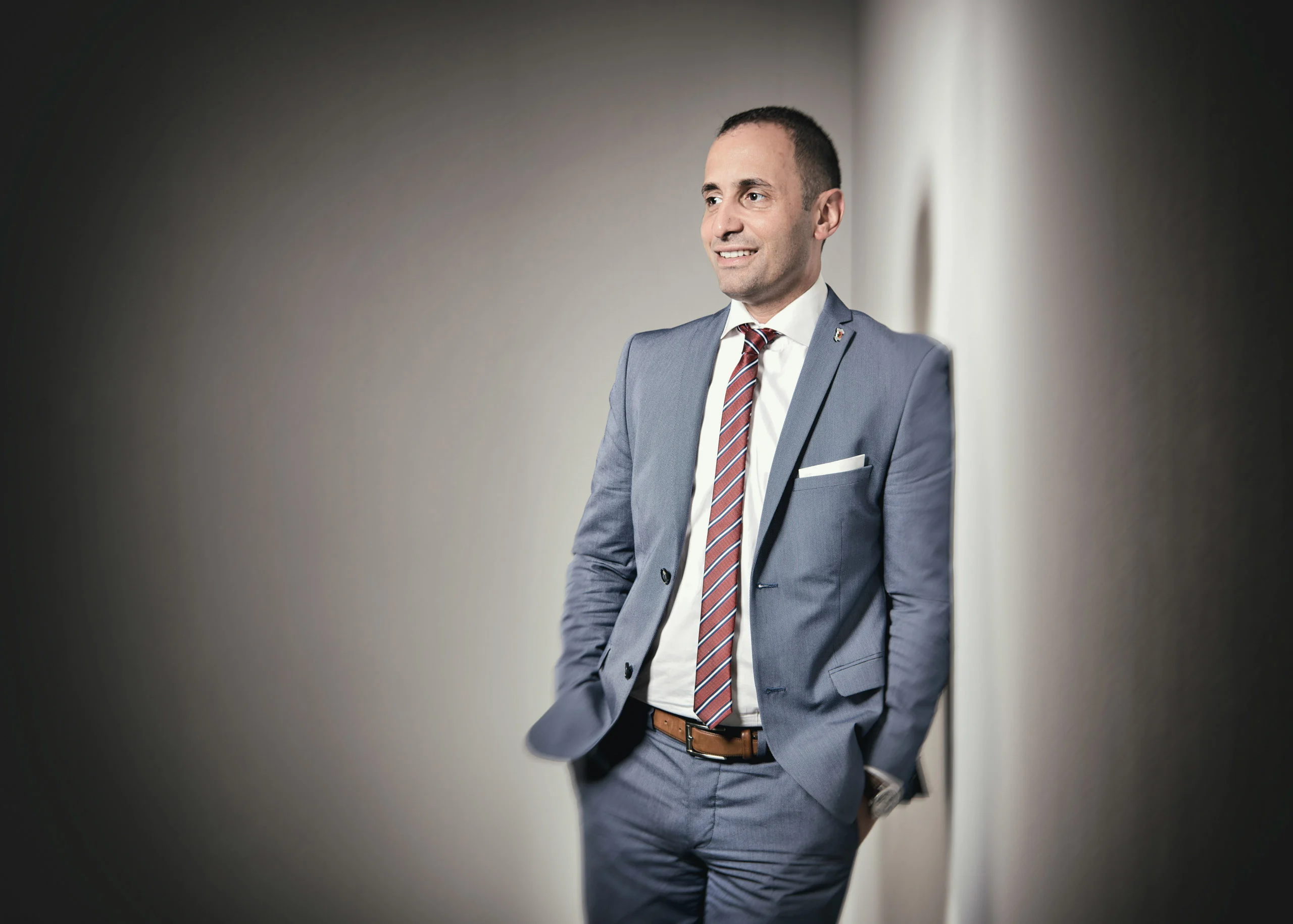 Business Portraits Fotogalerie 064 | Peter Lauritis Photography Mann im blauen Anzug mit Krawatte lehnt an einer hellen Wand