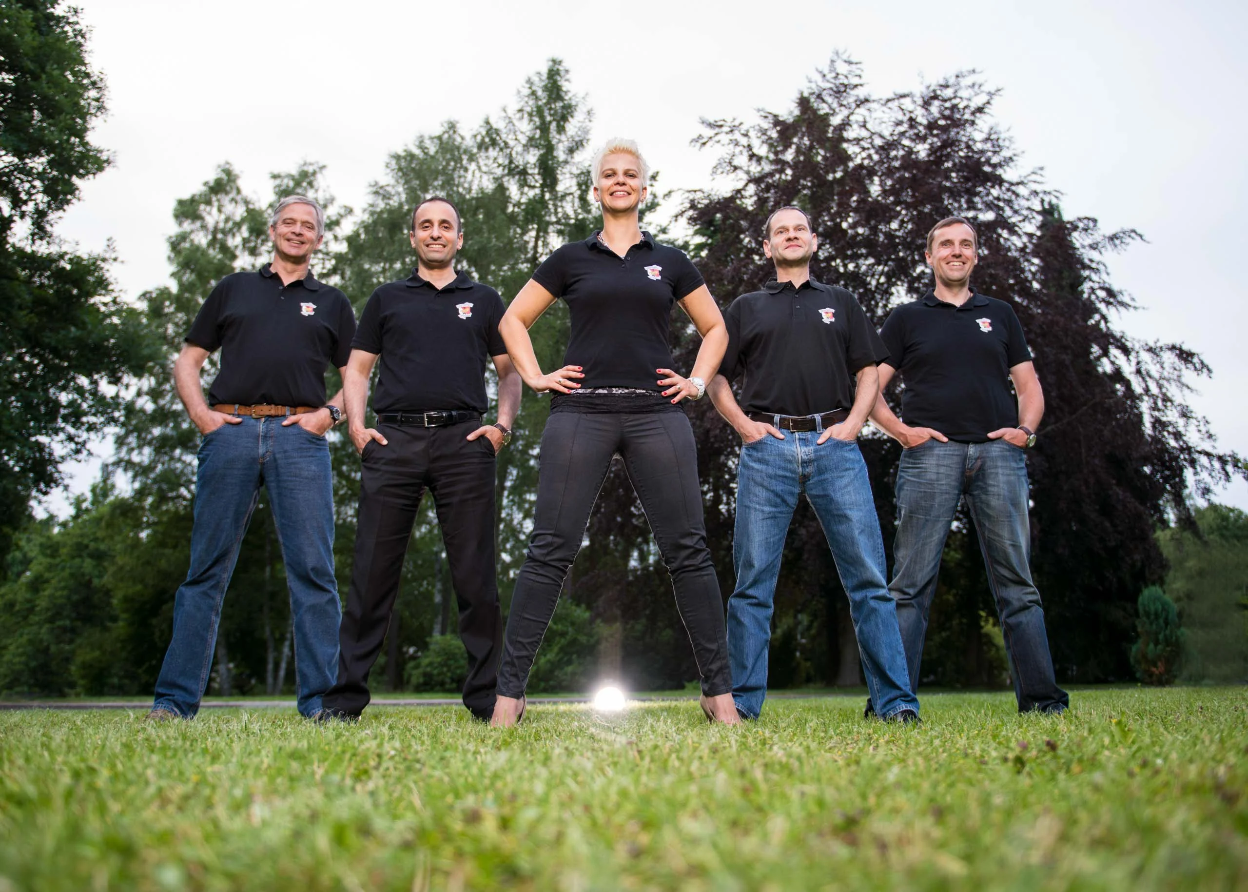 Business Portraits Fotogalerie 075 | Peter Lauritis Photography Fünf Personen in schwarzen Poloshirts stehen auf einer Wiese