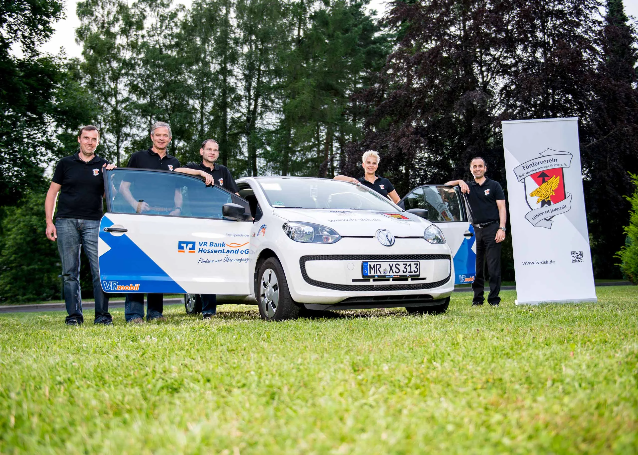 Business Portraits Fotogalerie 076 | Peter Lauritis Photography Gruppe in schwarzen Shirts steht neben einem beklebten Kleinwagen und einem Banner