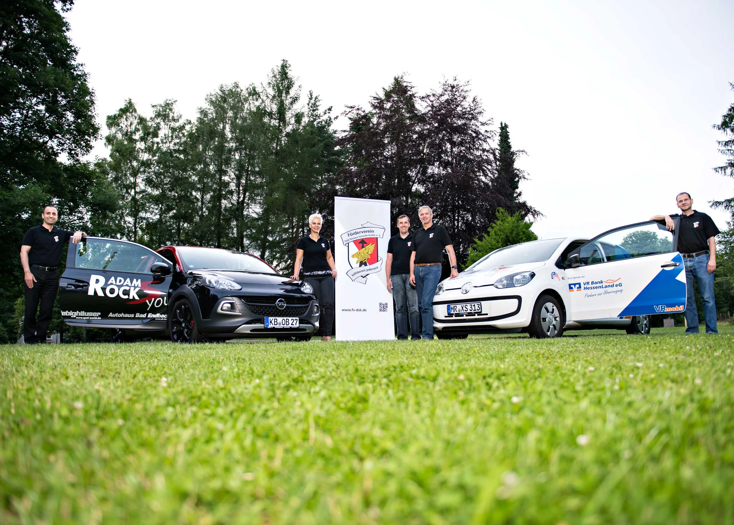 Business Portraits Fotogalerie 077 | Peter Lauritis Photography Gruppe mit zwei beklebten Autos und Banner auf einer Wiese