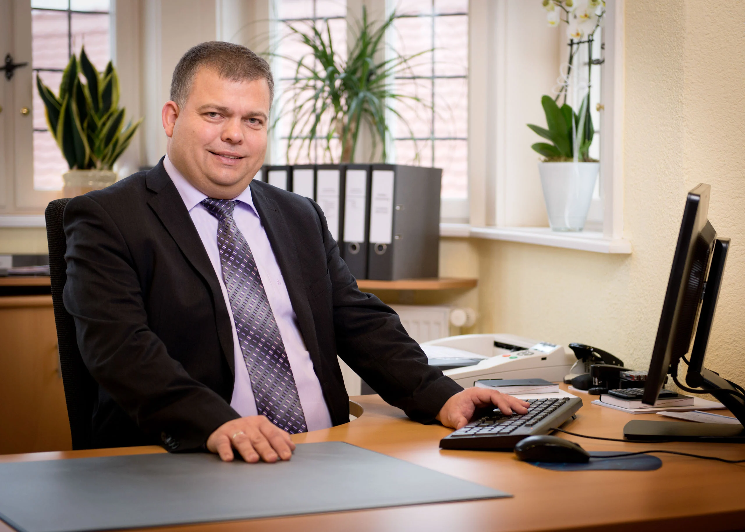 Business Portraits Fotogalerie 082 | Peter Lauritis Photography Mann im Anzug sitzt am Schreibtisch mit Computer