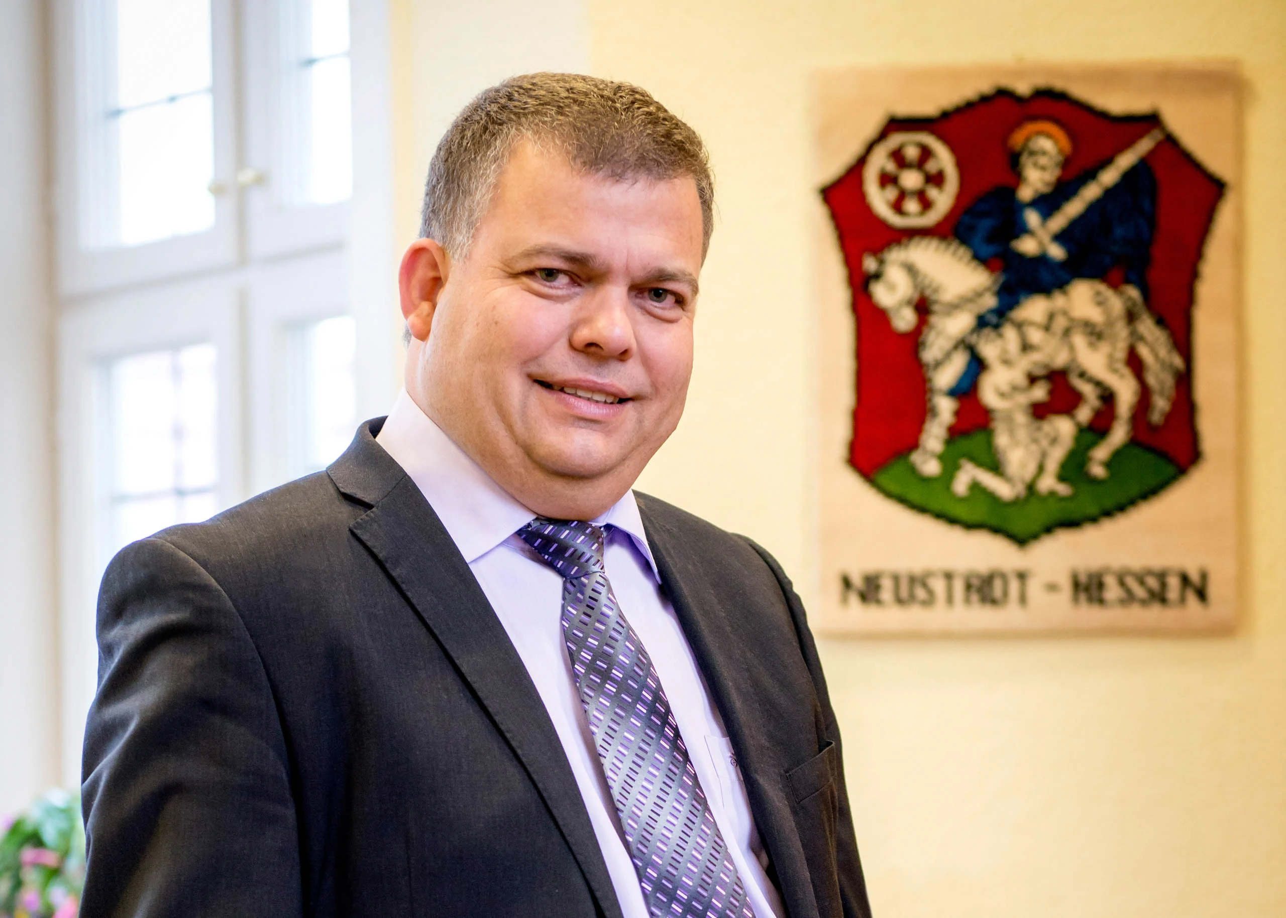 Business Portraits Fotogalerie 083 | Peter Lauritis Photography Mann im Anzug vor dem Stadtwappen von Neustadt (Hessen)