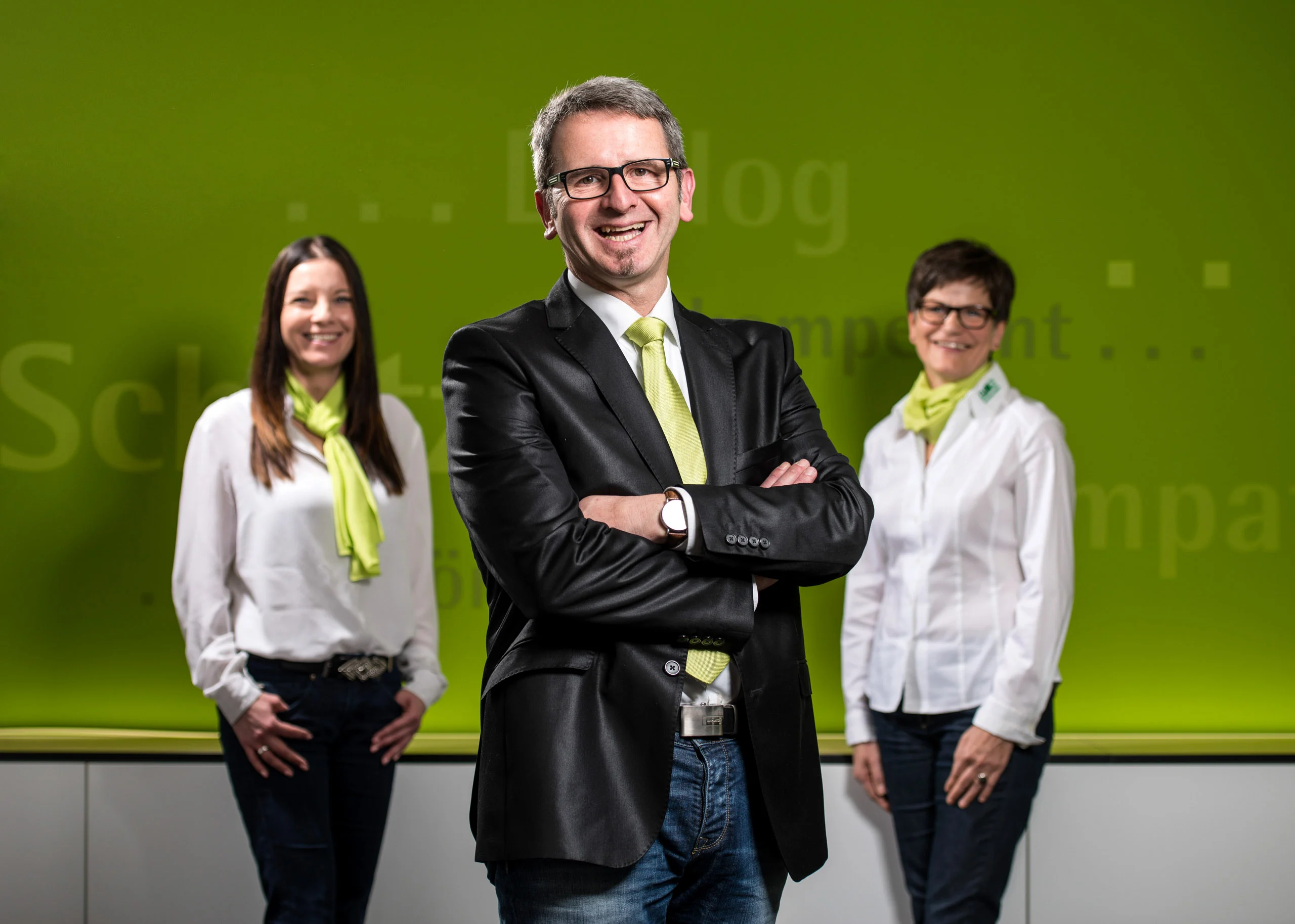 Business Portraits Fotogalerie 085 | Peter Lauritis Photography Mann mit verschränkten Armen zwischen zwei Mitarbeiterinnen vor grüner Wand