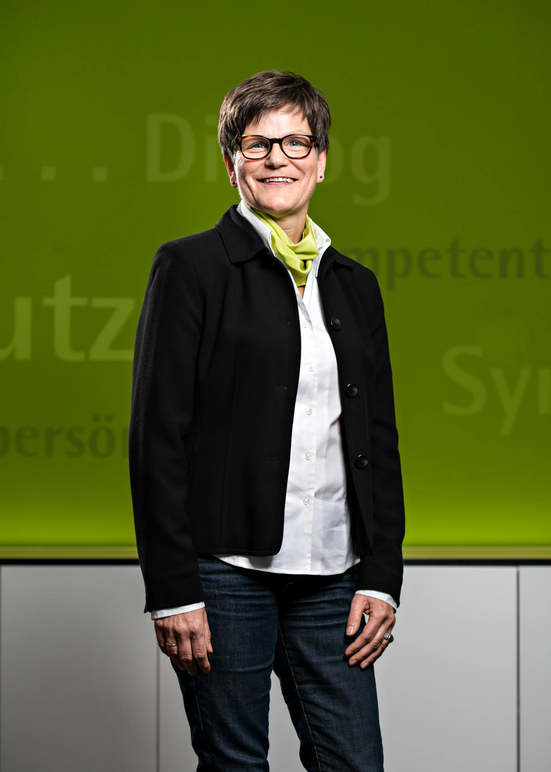 Business Portraits Fotogalerie 086 | Peter Lauritis Photography Frau mit kurzen Haaren, Brille und grünem Halstuch vor grüner Wand