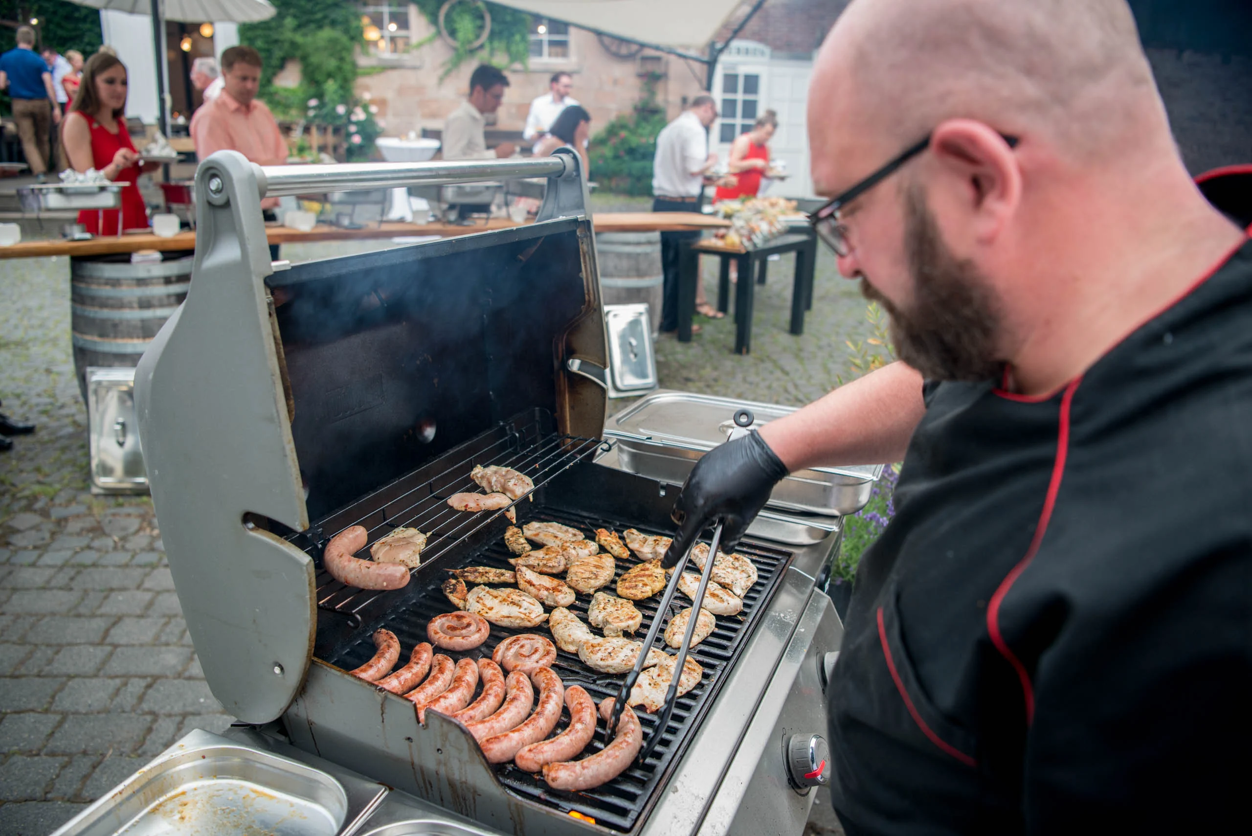 Hochzeitsfeier Fotogalerie 013 | Peter Lauritis Photography Grillmeister legt Würstchen und Fleisch auf den Grill