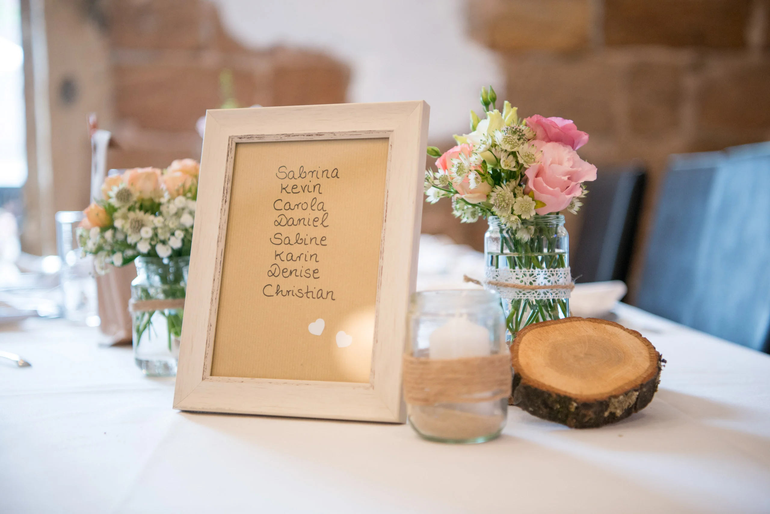 Hochzeitsfeier Fotogalerie 021 | Peter Lauritis Photography Tischkarte im Bilderrahmen mit Namen neben Blumen und Holzscheibe