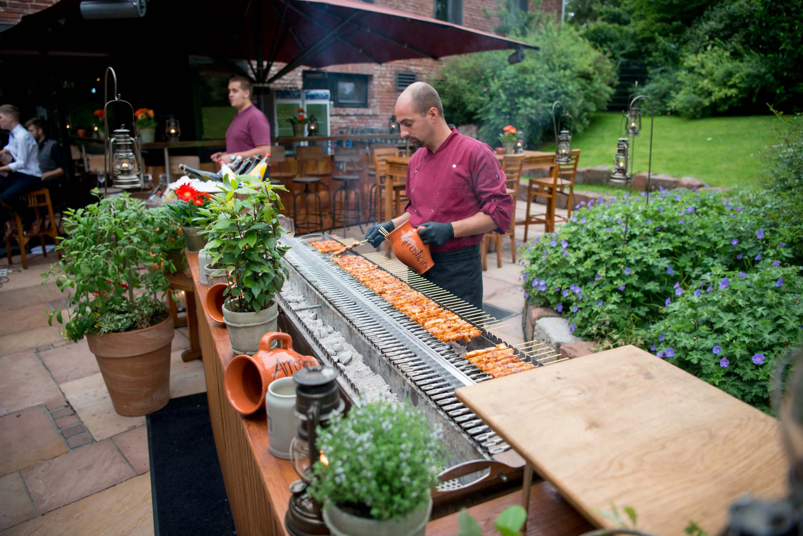 Hochzeitsfeier Fotogalerie 035 | Peter Lauritis Photography Koch grillt an einem langen Grill auf einer Terrasse