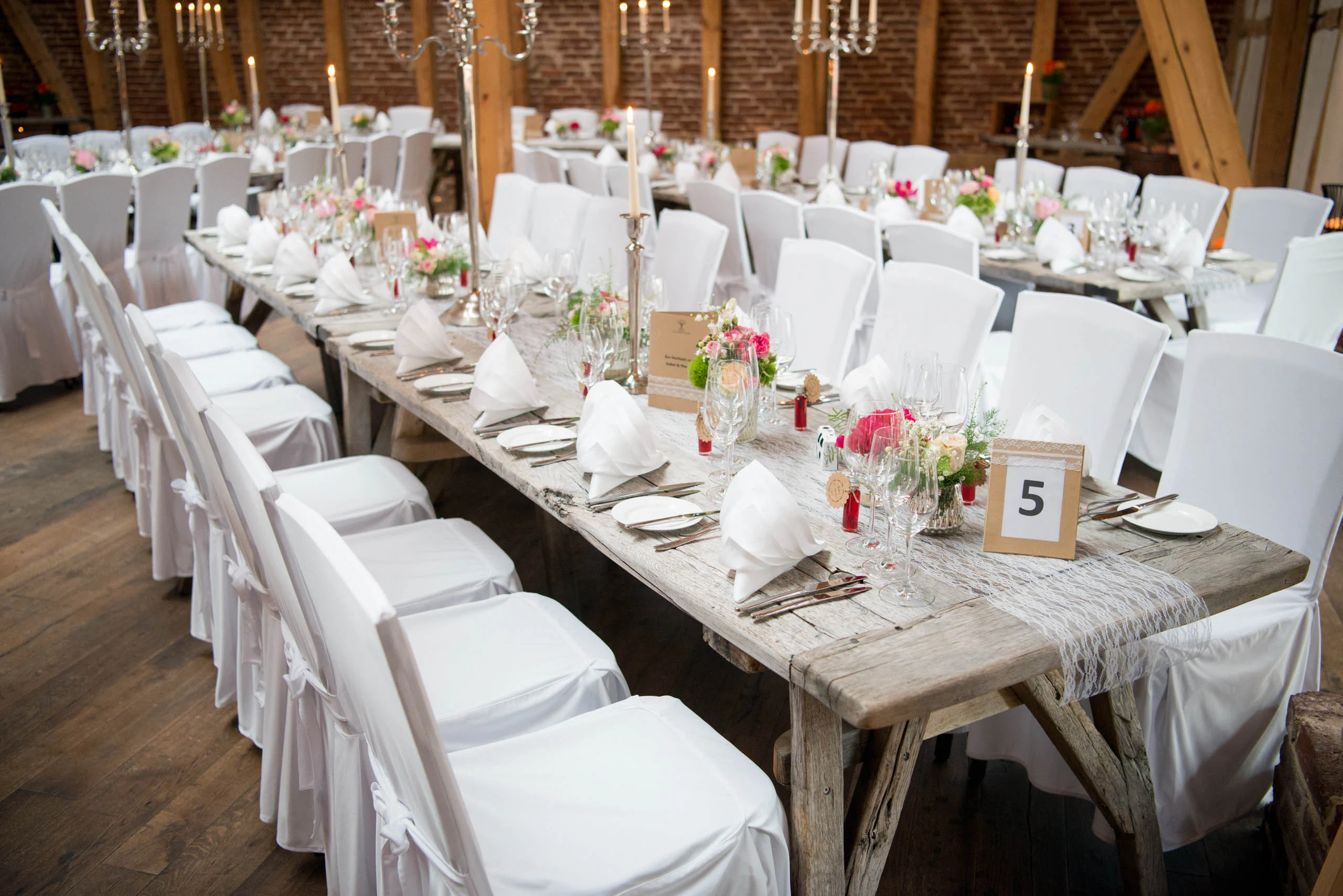 Hochzeitsfeier Fotogalerie 036 | Peter Lauritis Photography Lange Holztafel mit weißen Stuhlhussen und Blumen in einer Scheune