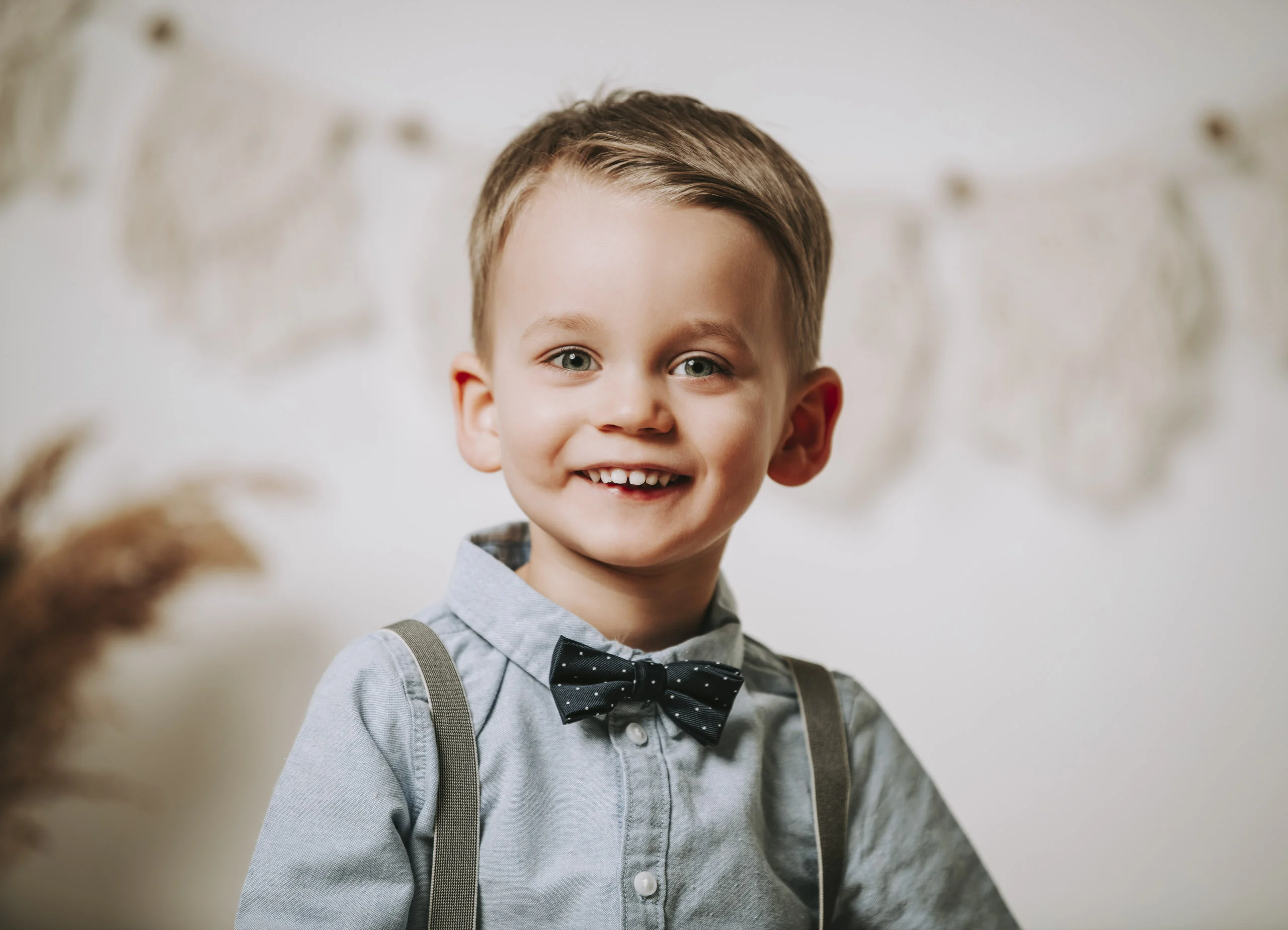 Porträt eines Jungen mit Fliege und Hosenträgern, der in die Kamera lächelt