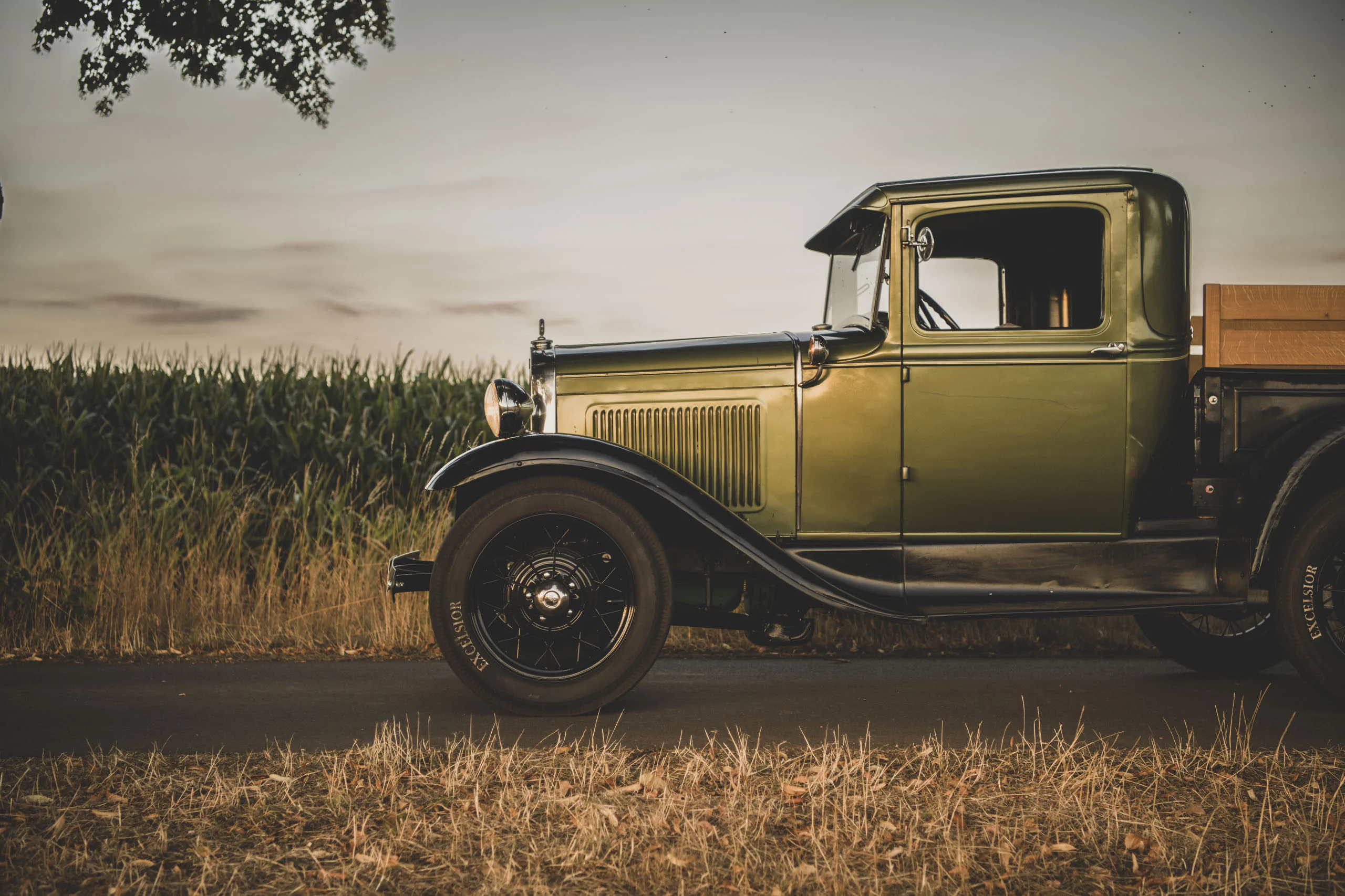 Auto-Fotoshooting: grüner Oldtimer-Pick-up in der Seitenansicht an einem Feldweg