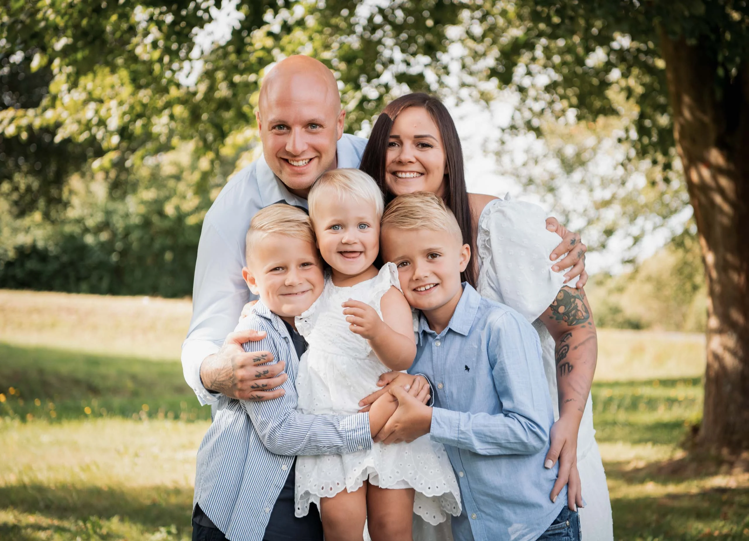 Einschulungsfotos Aktion 02 | Peter Lauritis Photography Familie mit drei Kindern umarmt sich lachend im Grünen unter einem Baum