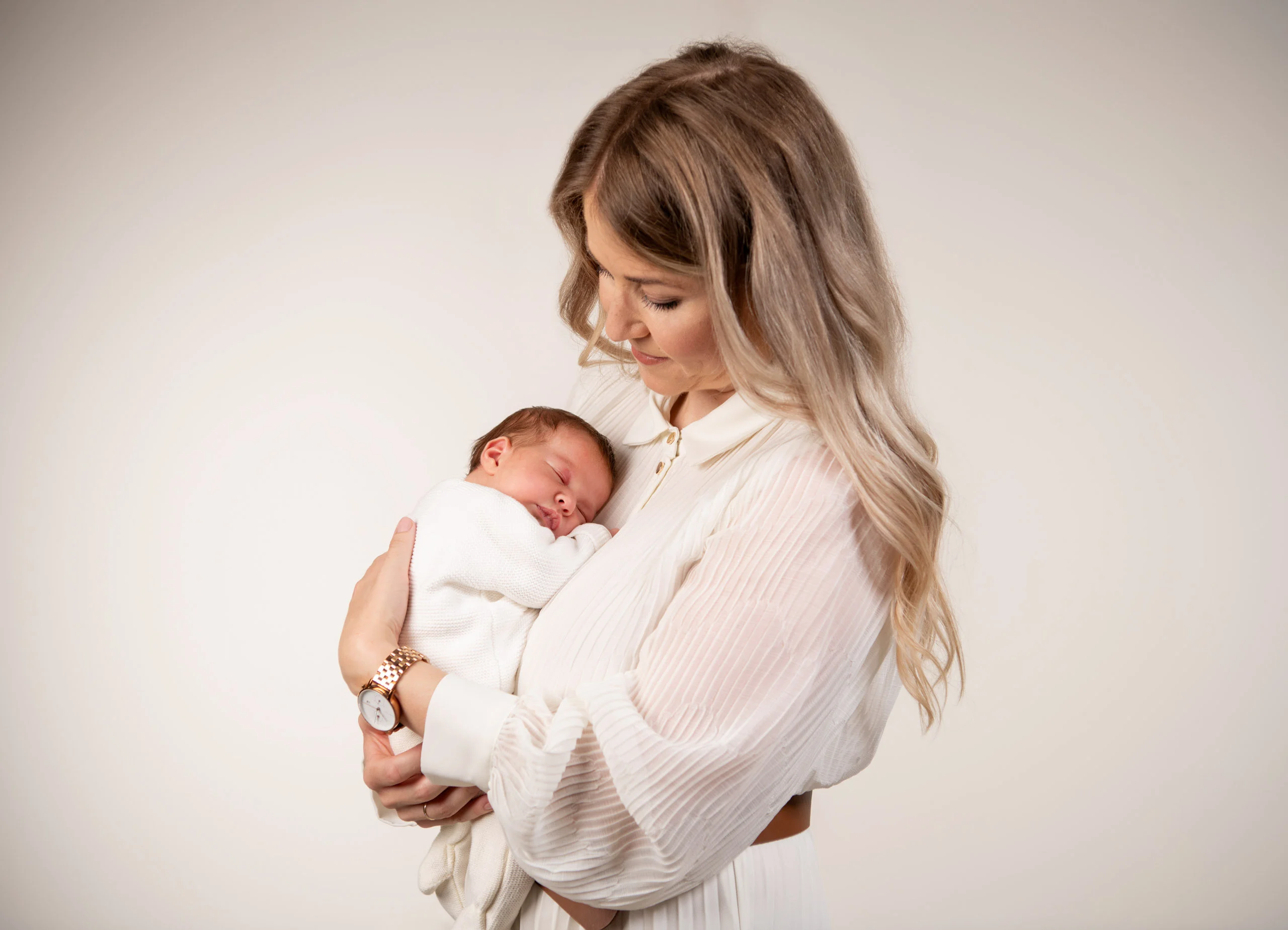 Baby- und Newbornfotos Produktbild 04 | Peter Lauritis Photography Frau im weißen Kleid hält ein schlafendes Neugeborenes im Arm