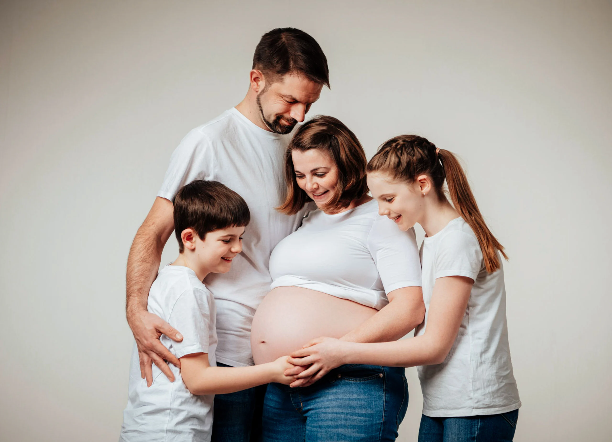 Babybauch Komplettpaket Produktbild 05 | Peter Lauritis Photography Familie mit zwei Kindern legt die Hände auf den Babybauch der Schwangeren in der Mitte