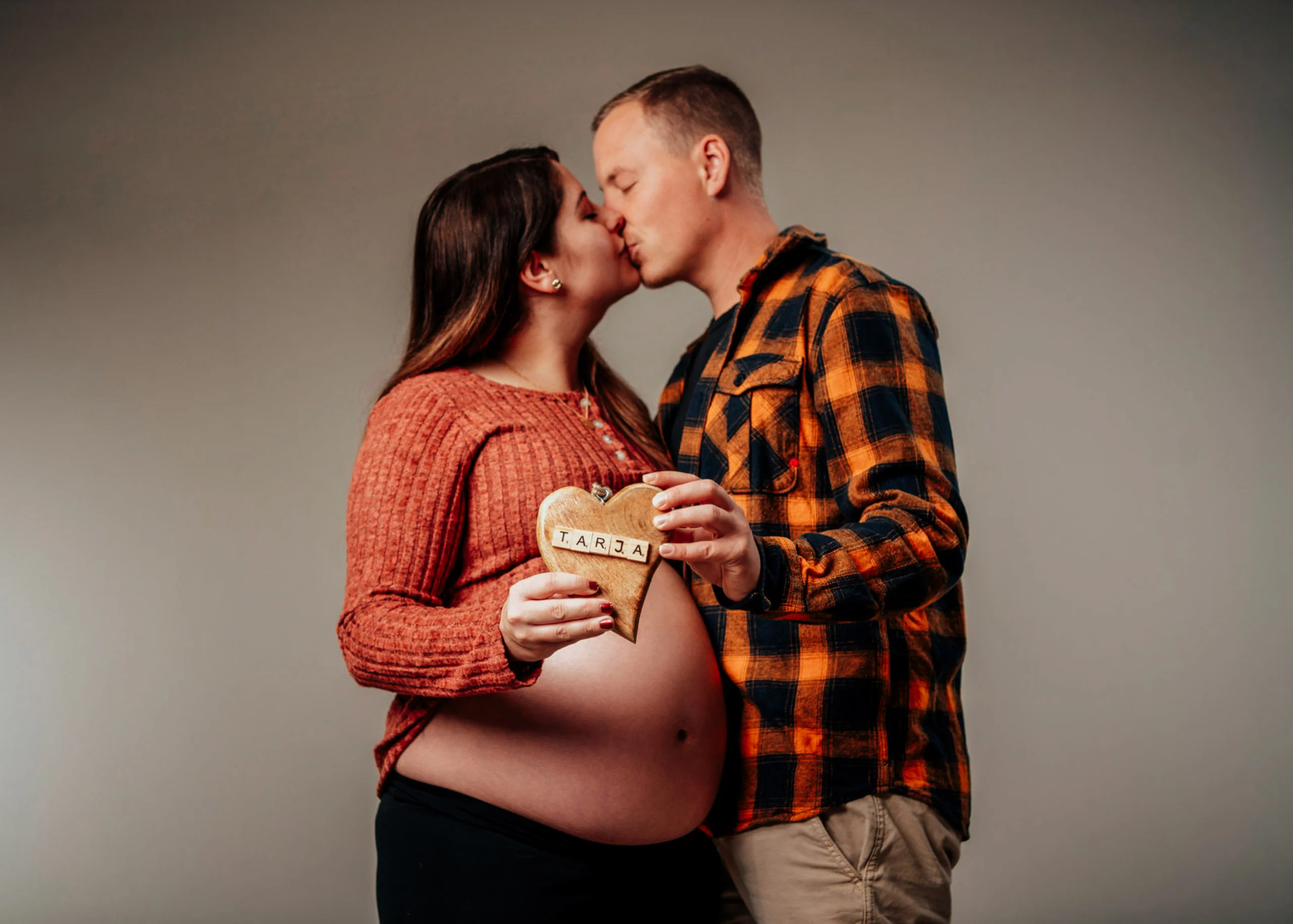 Babybauch Komplettpaket Produktbild 08 | Peter Lauritis Photography Paar küsst sich, die Schwangere hält ein Holzherz vor ihren Babybauch