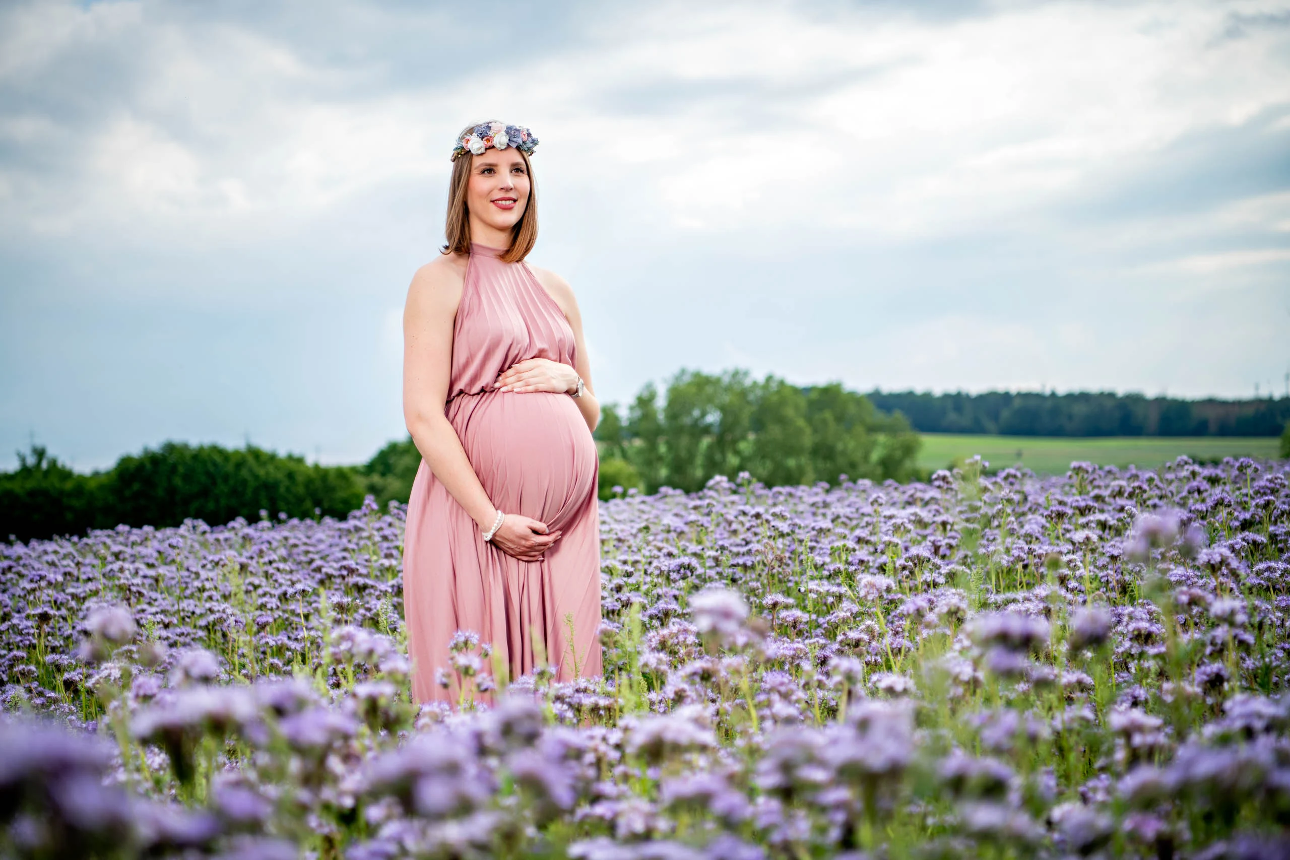 Babybauch Komplettpaket Produktbild 11 | Peter Lauritis Photography Schwangere im rosa Kleid mit Blumenkranz steht in einem lila blühenden Feld