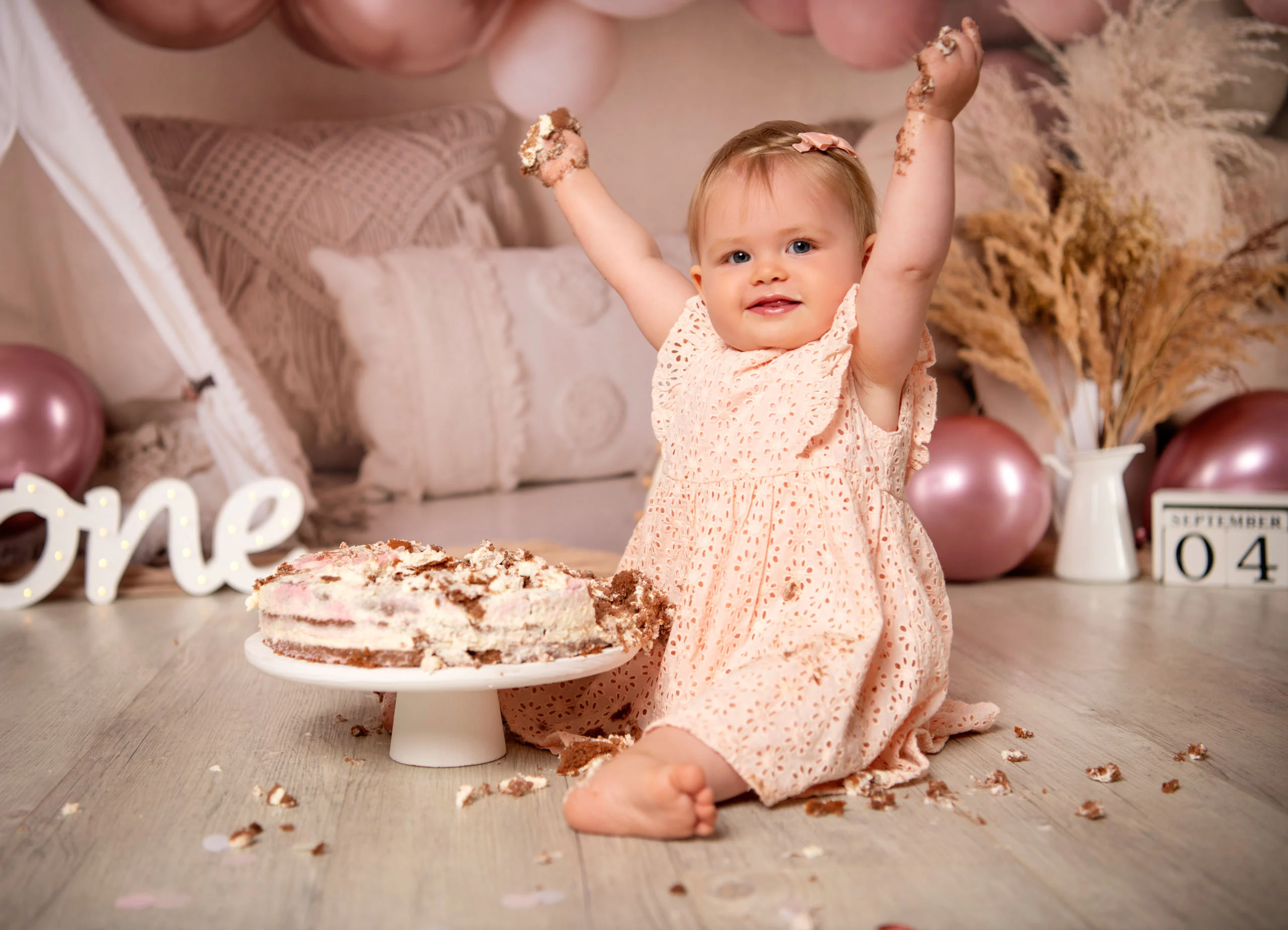 Cake Smash Produktbild 08 | Peter Lauritis Photography Mädchen im rosa Kleid reißt jubelnd die Arme hoch, vor ihm die angegessene Torte