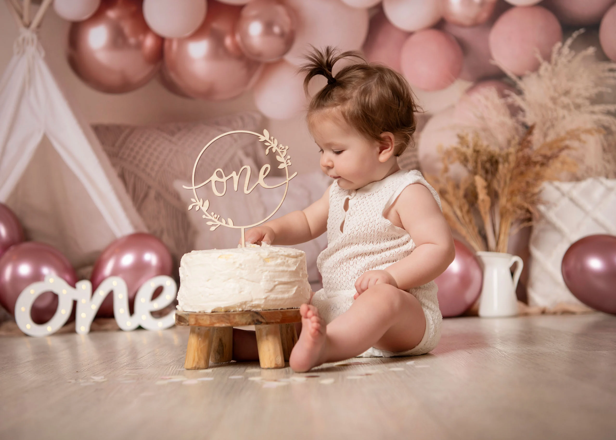 Cake Smash Produktbild 14 | Peter Lauritis Photography Kleinkind tippt vorsichtig mit dem Finger in die weiße Torte mit „one“-Aufsatz