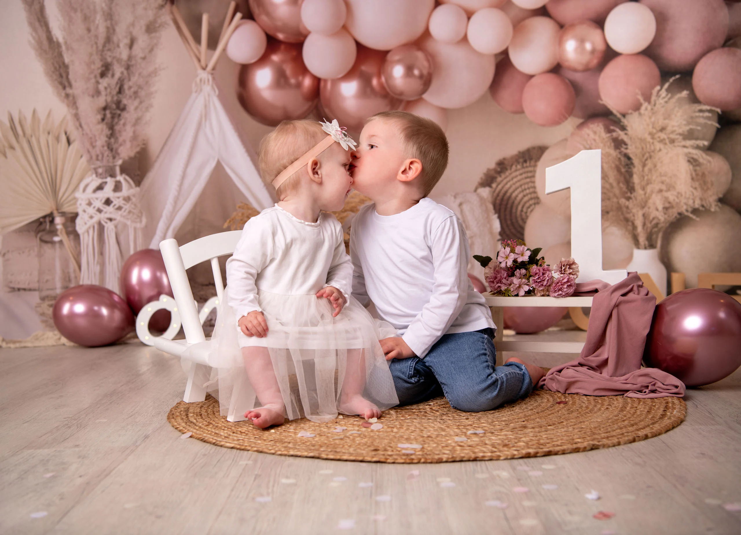 Cake Smash Produktbild 22 | Peter Lauritis Photography Kleiner Junge gibt dem Mädchen im Tüllkleid einen Kuss, beide sitzen vor rosa Ballonkulisse