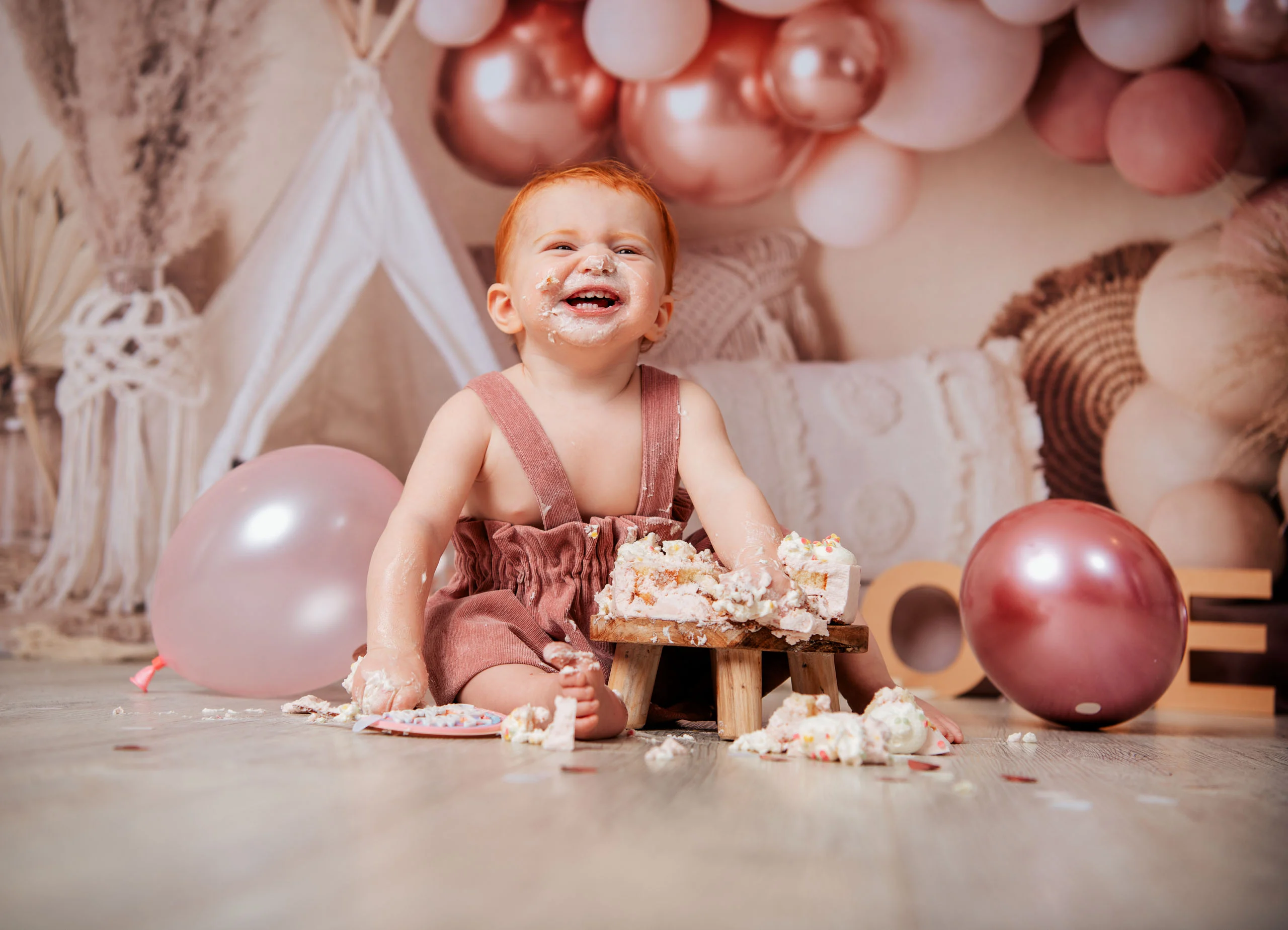 Cake Smash Produktbild 23 | Peter Lauritis Photography Rothaariges Kleinkind mit Sahne im Gesicht lacht hinter einer zerdrückten Torte