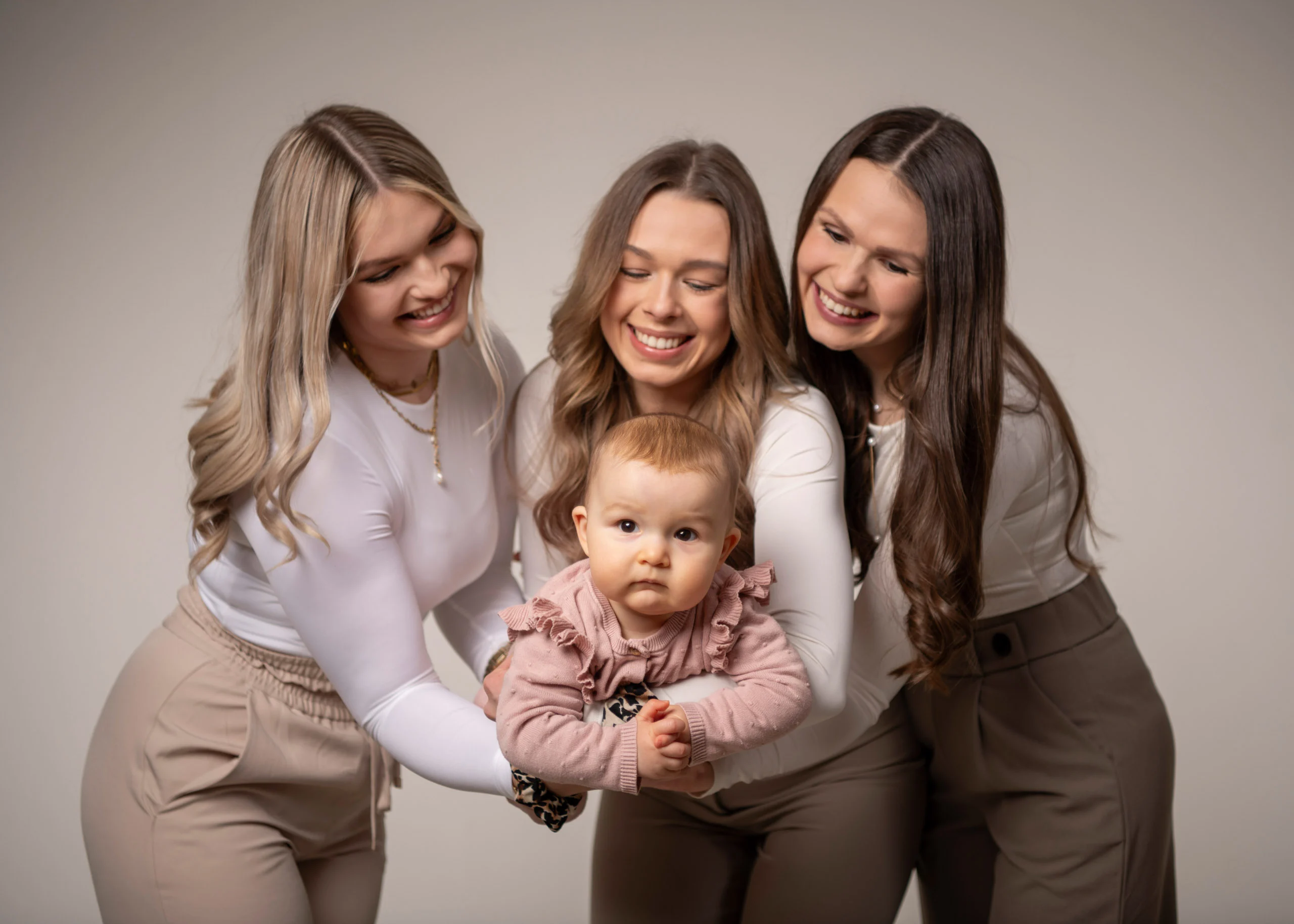 Familienfotos Produktbild 02 | Peter Lauritis Photography Drei junge Frauen beugen sich lachend über ein Baby, das in ihrer Mitte steht