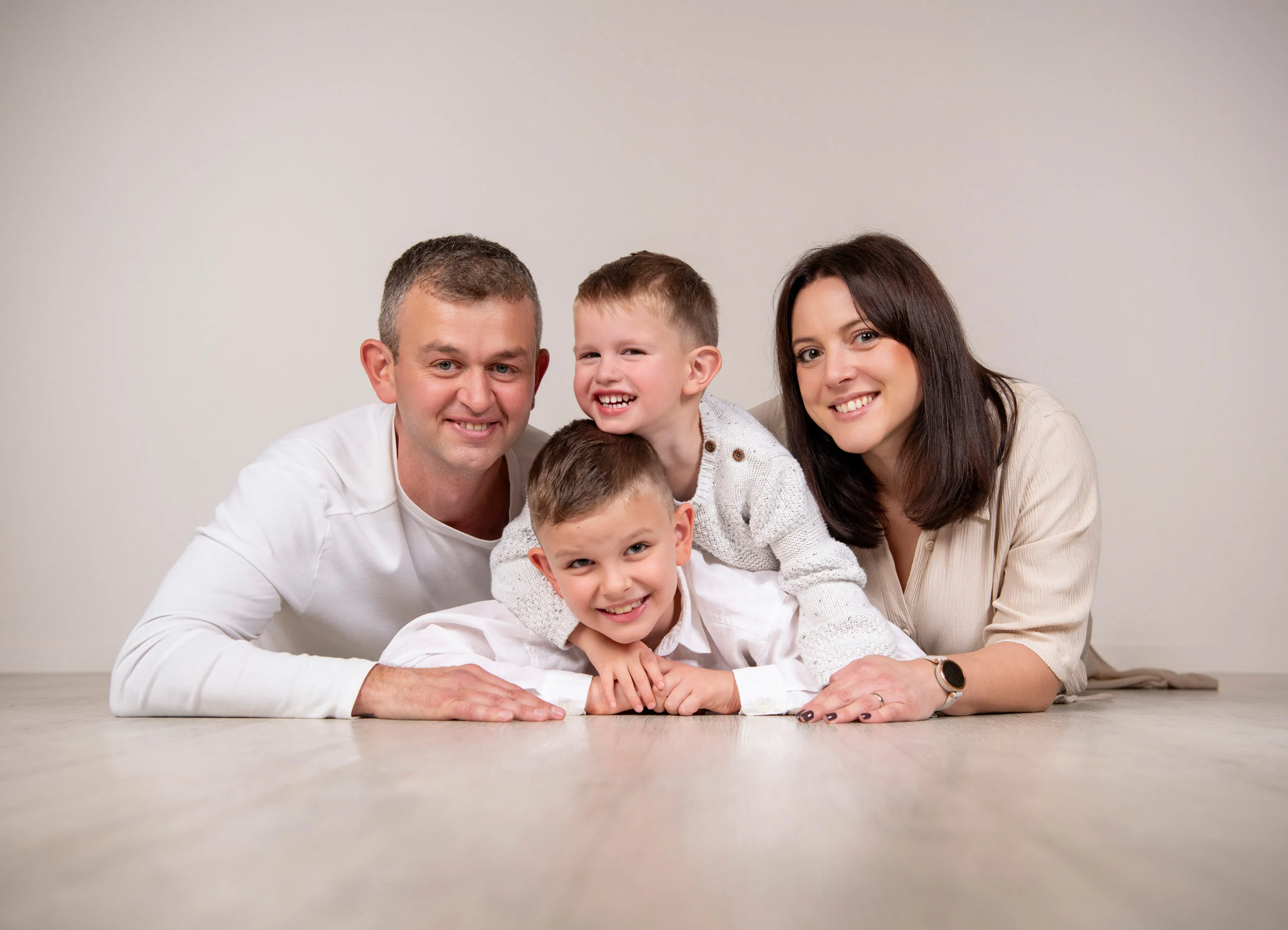 Familienfotos Produktbild 08 | Peter Lauritis Photography Eltern liegen auf dem Studioboden, zwischen ihnen zwei lachende Jungen