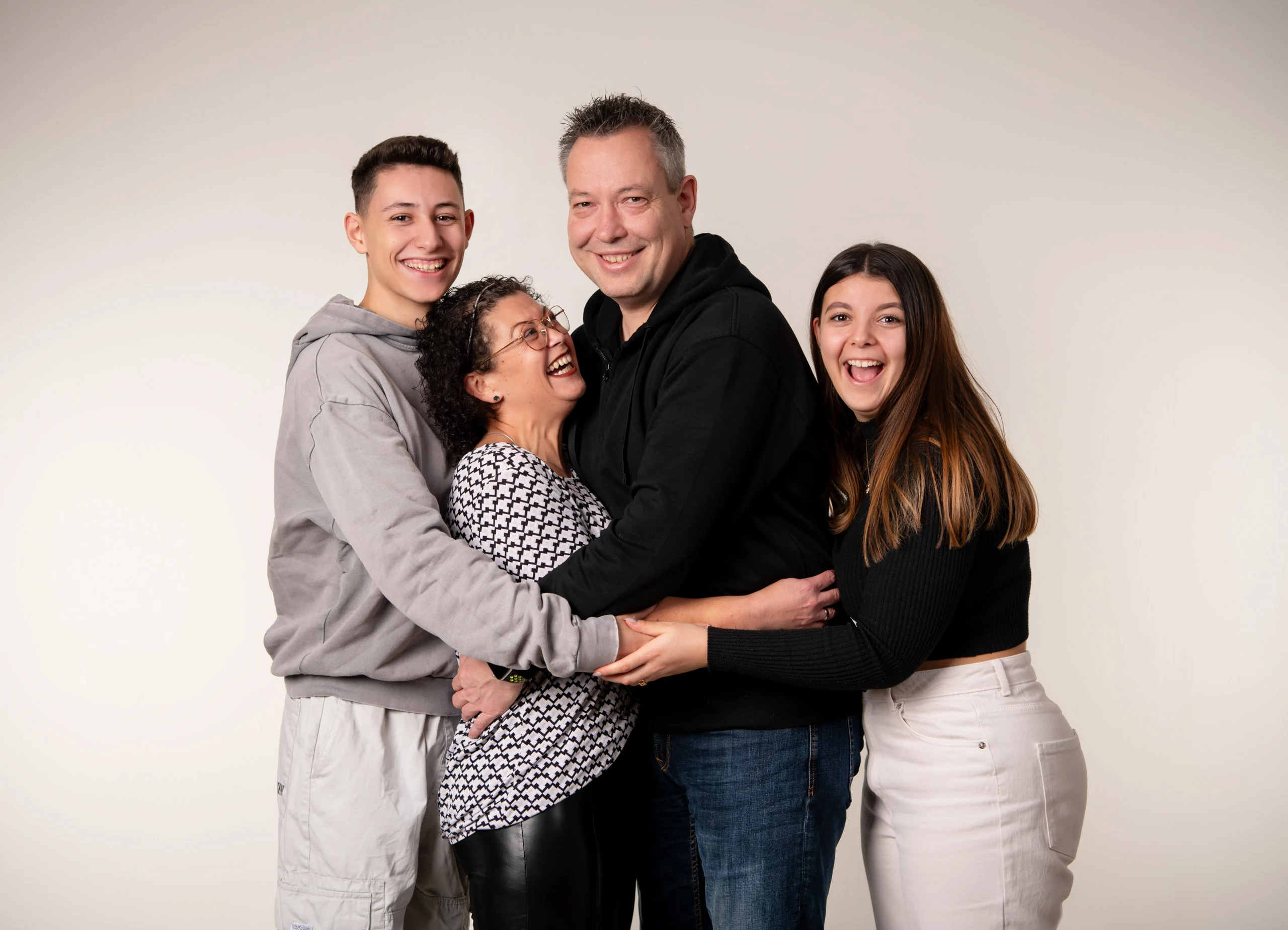 Familienfotos Produktbild 12 | Peter Lauritis Photography Vier Personen umarmen sich lachend im Fotostudio
