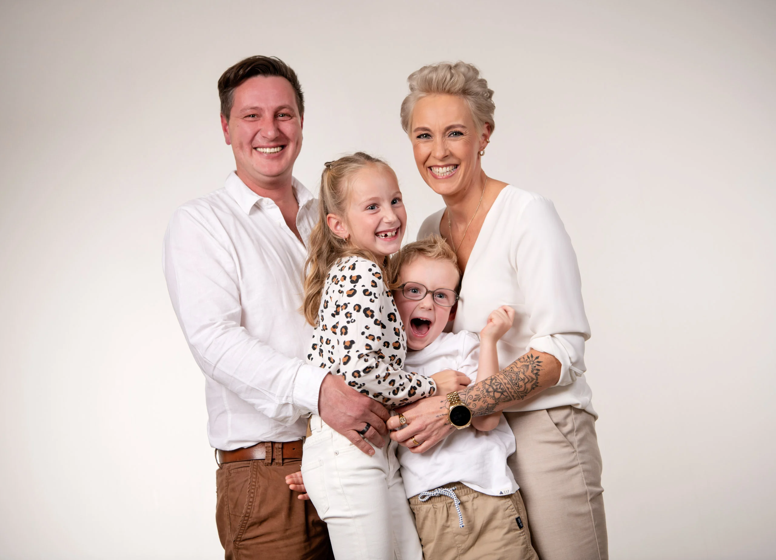 Familienfotos Produktbild 19 | Peter Lauritis Photography Familie mit zwei Kindern in Weiß umarmt sich lachend
