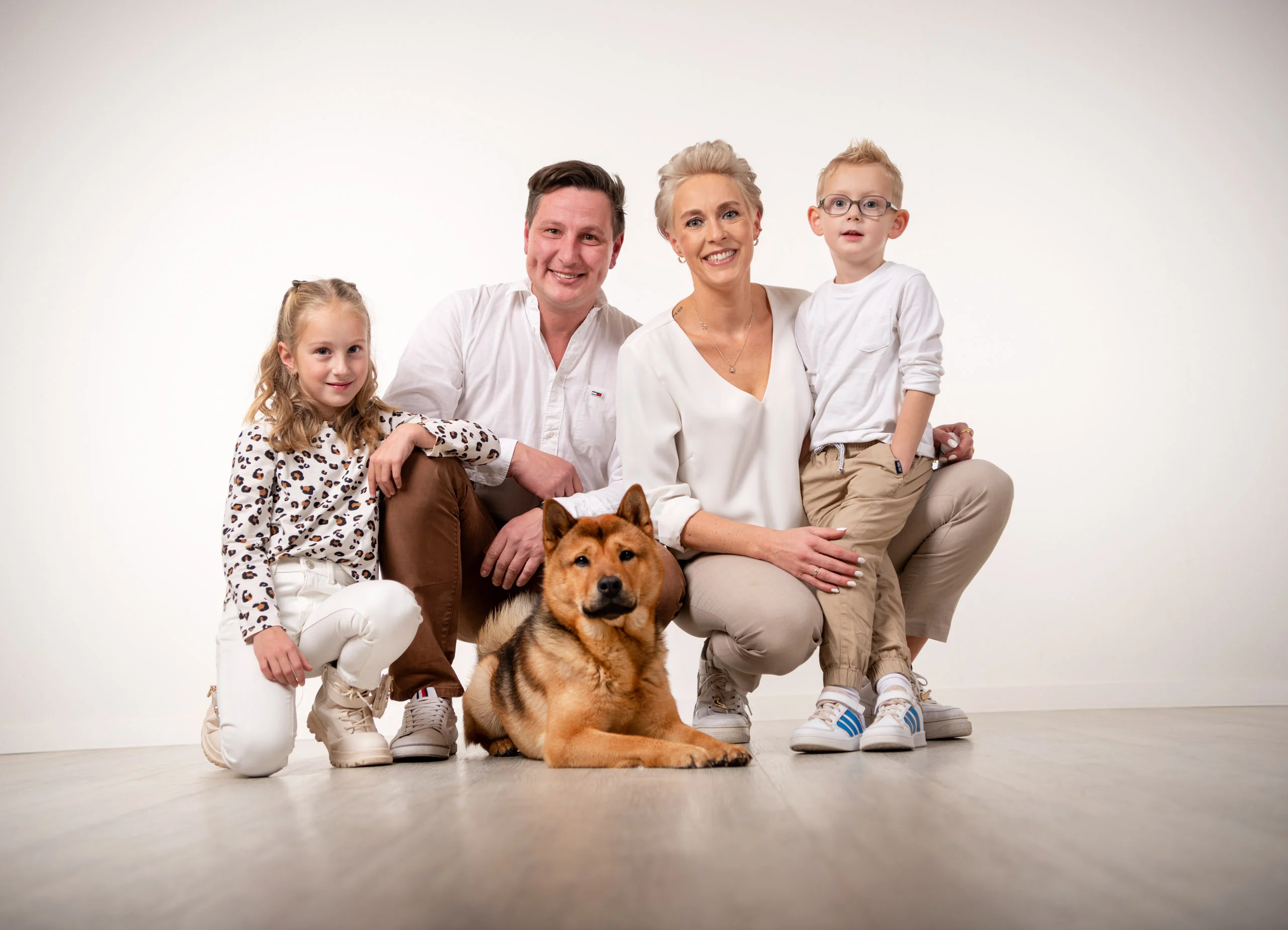 Familienfotos Produktbild 20 | Peter Lauritis Photography Familie mit zwei Kindern hockt im Studio um ihren rotbraunen Hund