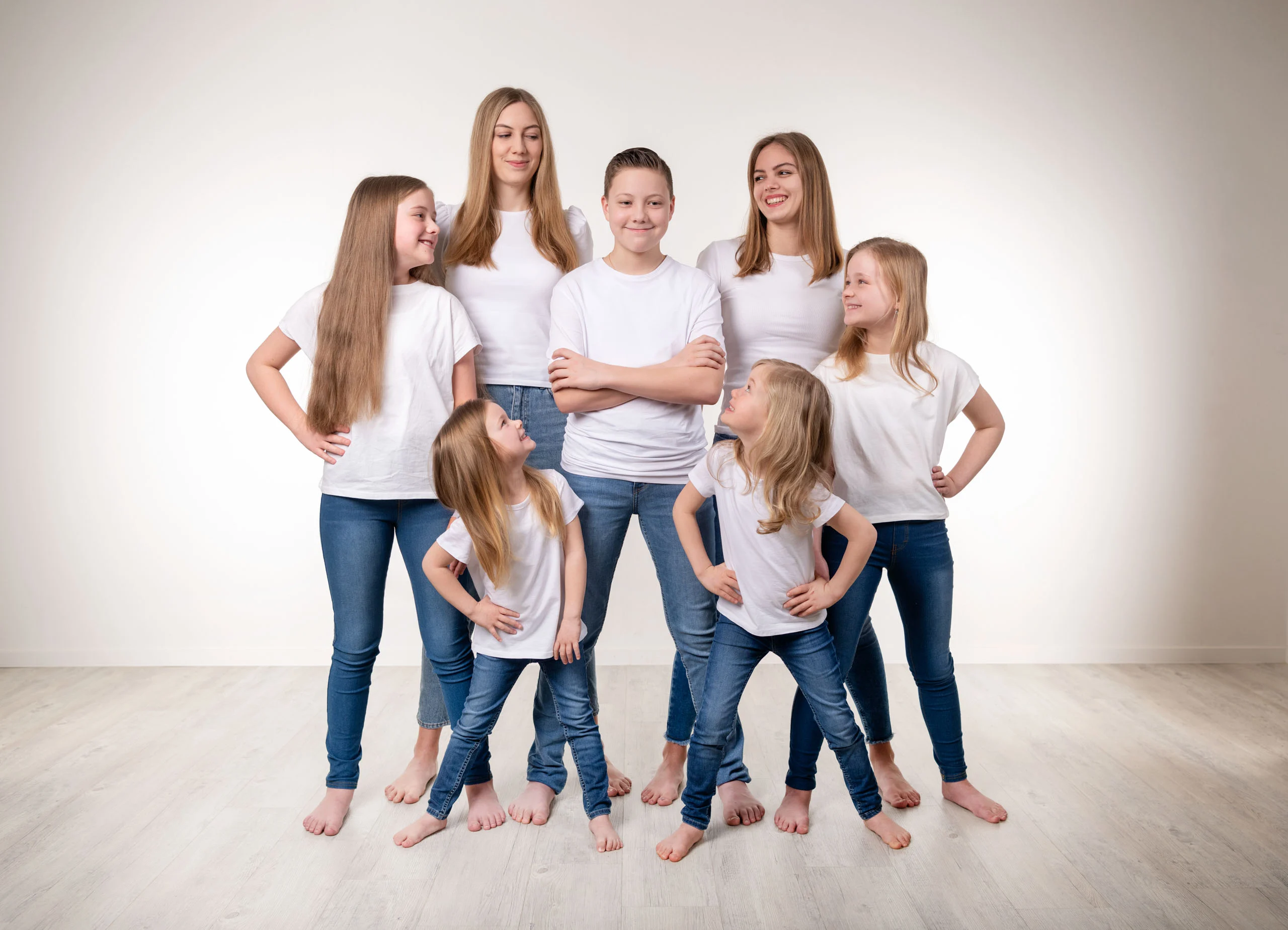 Familienfotos Produktbild 21 | Peter Lauritis Photography Gruppe aus sieben Kindern und Jugendlichen in weißen Shirts und Jeans steht barfuß im Studio