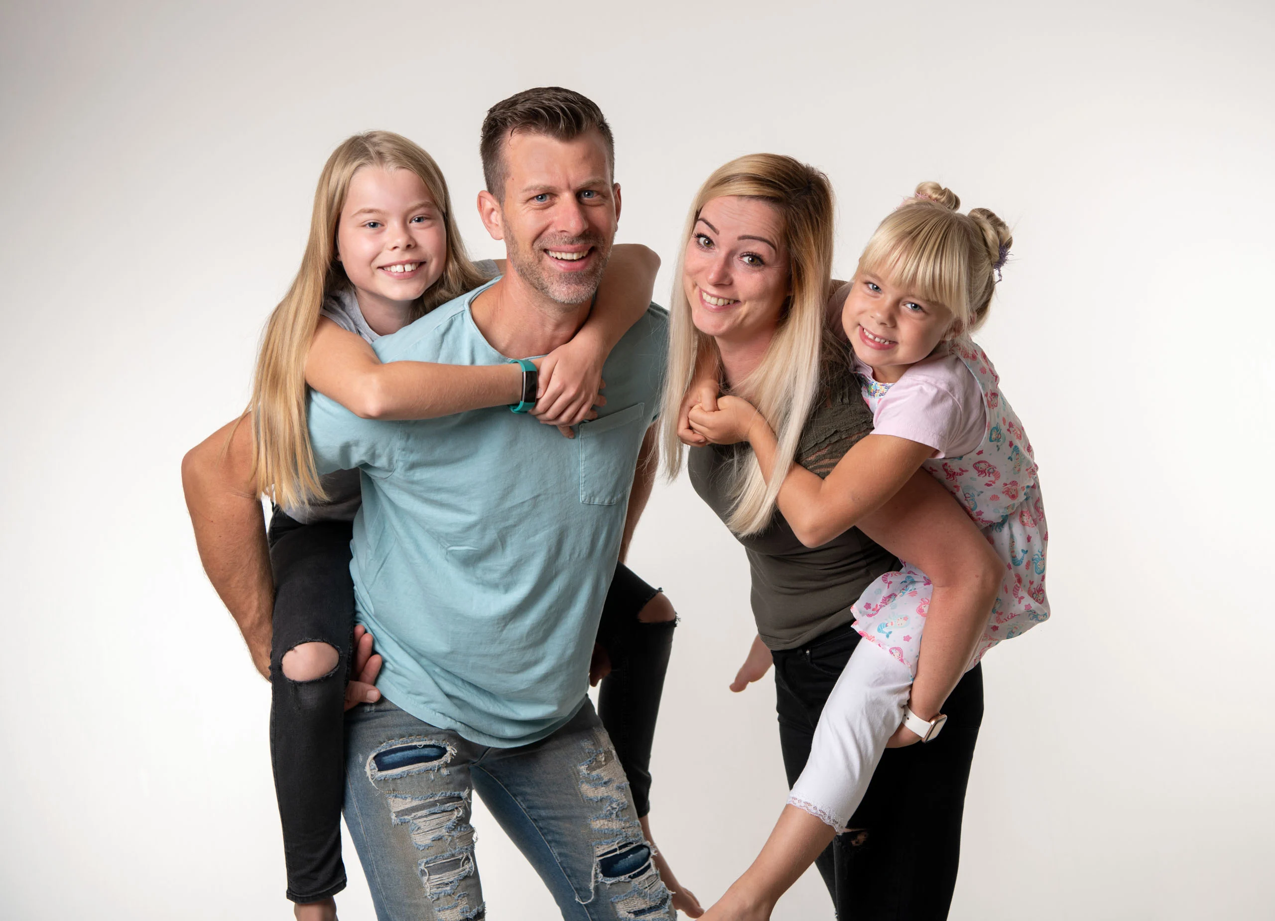 Familienfotos Produktbild 24 | Peter Lauritis Photography Eltern tragen zwei lachende Mädchen huckepack
