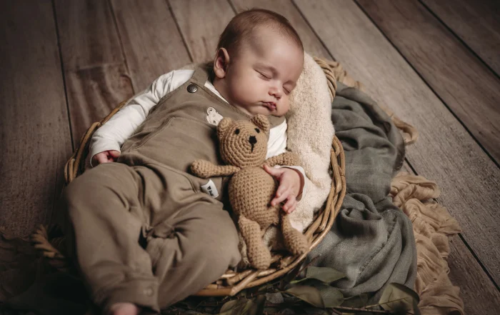 Baby schläft mit handgemachtem Teddy | Peter Lauritis Photography Nahaufnahme eines schlafenden Babys im Korb, das einen handgemachten gehäkelten Teddybären festhält