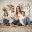 Familienfotos mit Hund: Eltern, Tochter und Sohn sitzen lachend auf Juteteppichen, in der Mitte ihr Mops