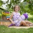 Fotoshooting zur Einschulung: Mädchen sitzt mit lila Schultüte vor einem Holzschild Schulkind, daneben ein bunter Rechenschieber