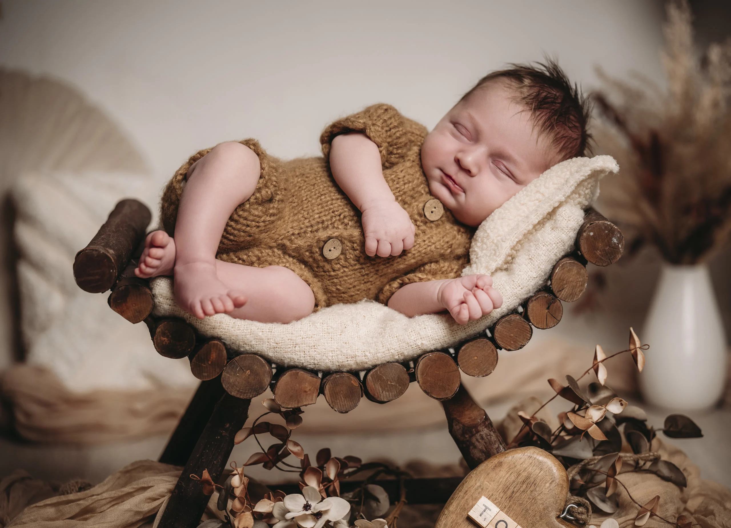 neugeborene baby holzliege | Peter Lauritis Photography Schlafendes Neugeborenes im braunen Strickanzug auf einer kleinen Holzliege mit weichem Fell – Neugeborenen-Fotoshooting im Fotostudio