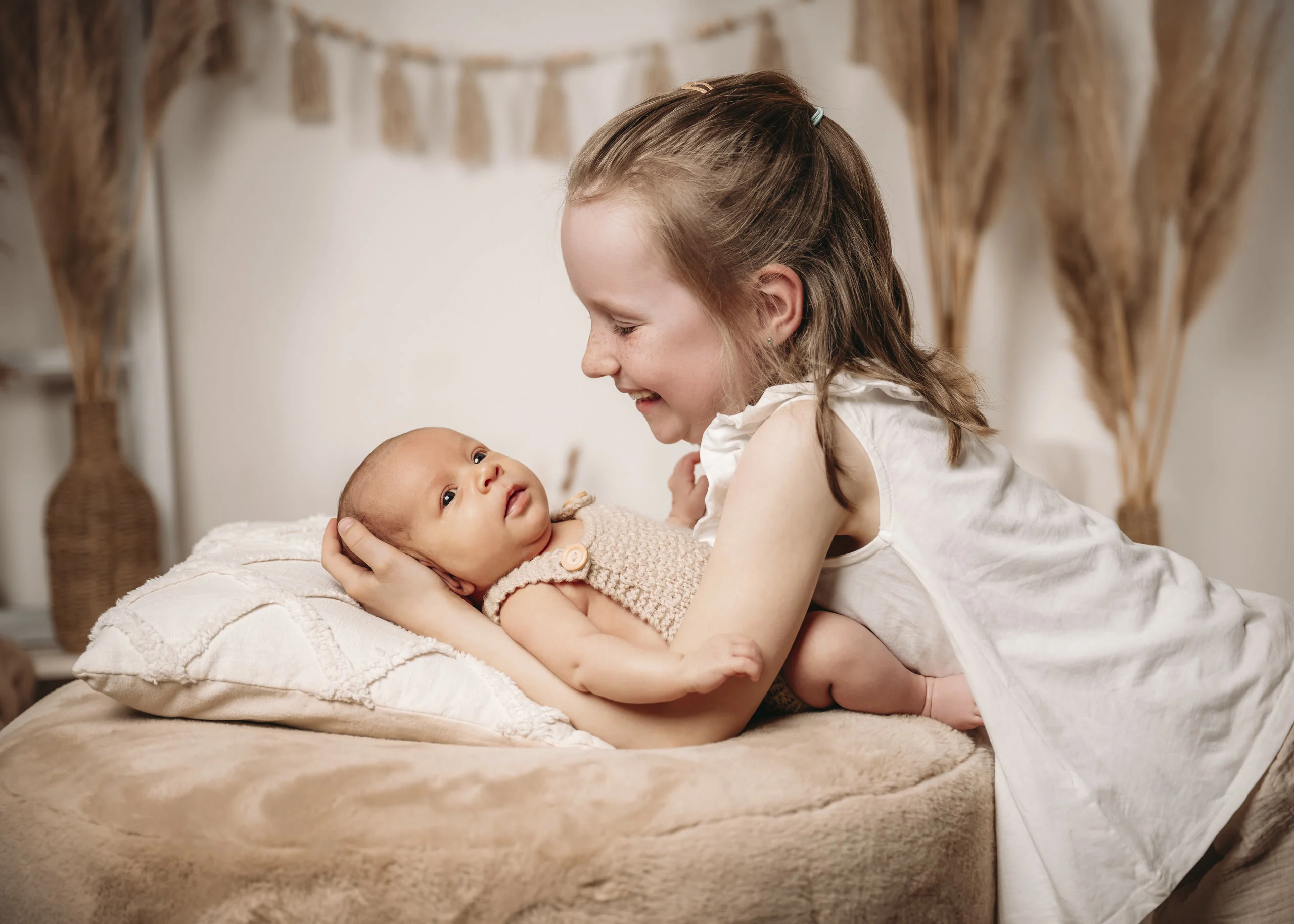 neugeborene grosse schwester haelt bruder | Peter Lauritis Photography Große Schwester hält ihren neugeborenen Bruder liebevoll auf einem Kissen – Neugeborenen-Fotoshooting mit Geschwisterkind