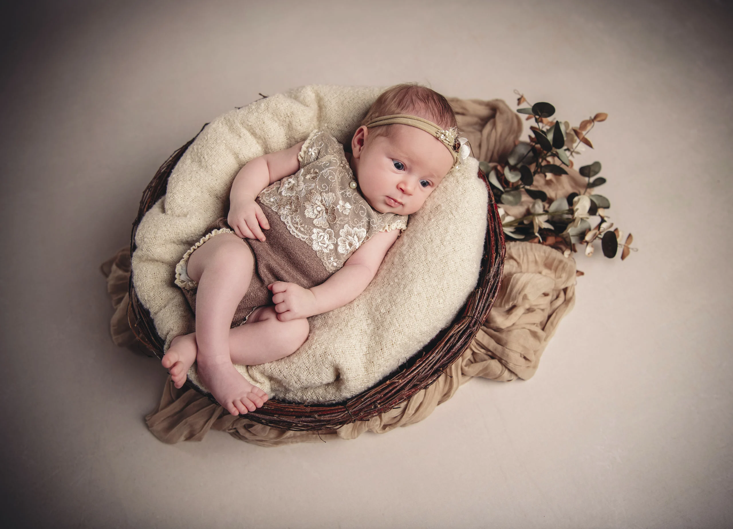 neugeborene maedchen im korb | Peter Lauritis Photography Neugeborenes Mädchen mit Haarband liegt eingekuschelt in einem runden Korb, von oben fotografiert – Babyfotos beim Neugeborenen-Fotoshooting