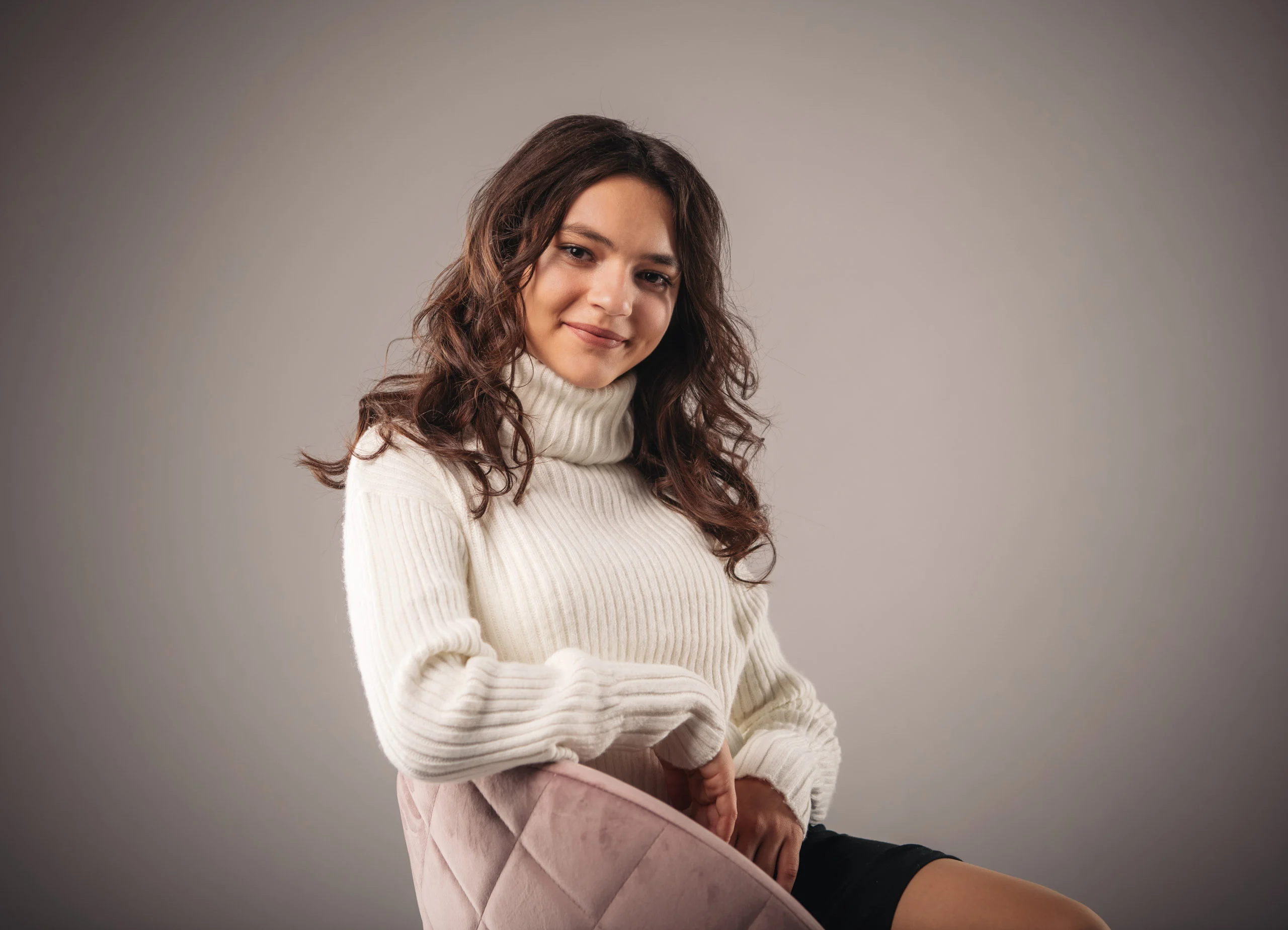 portraitfotos frau weisser pullover | Peter Lauritis Photography Junge Frau im weißen Rollkragenpullover lächelt auf einem Stuhl – natürliche Portraitfotos