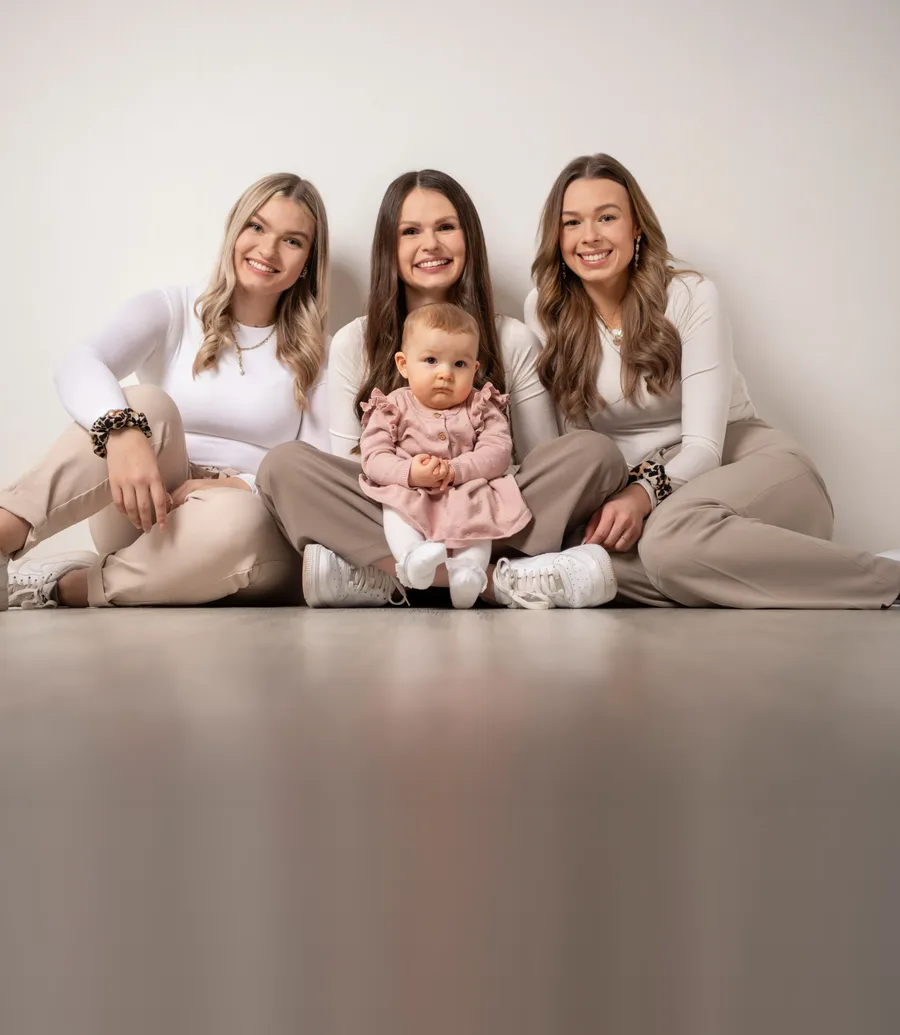 startseite familie geschwister Kachel | Peter Lauritis Photography Familienfoto vom Fotograf in Neustadt (Hessen): drei junge Frauen und ein Kleinkind in hellen Outfits sitzen im Fotostudio
